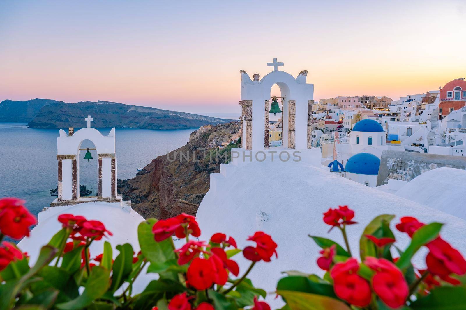 Sunset at the Island Of Santorini Greece, beautiful whitewashed village Oia with church and windmill during sunset, streets of Oia Santorini during summer vacation at the Greek Island