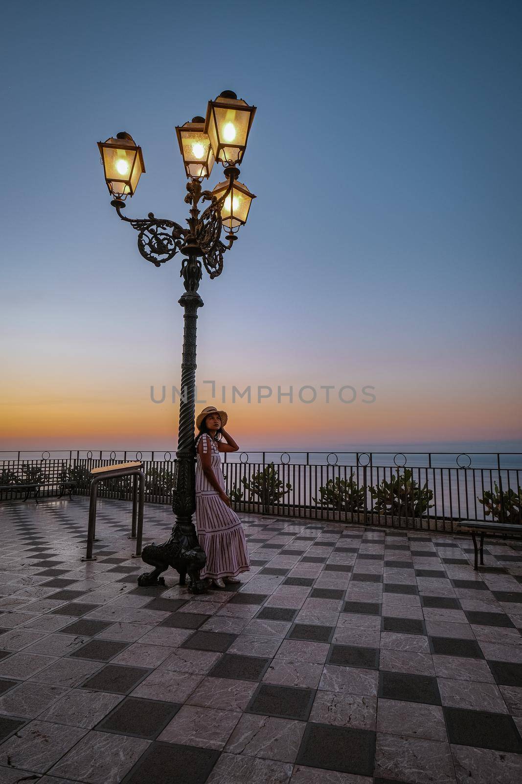 Taormina Sicily, Belvedere of Taormina and San Giuseppe church on the square Piazza IX Aprile in Taormina. Sicily, Italy. couple under lantern during sunset