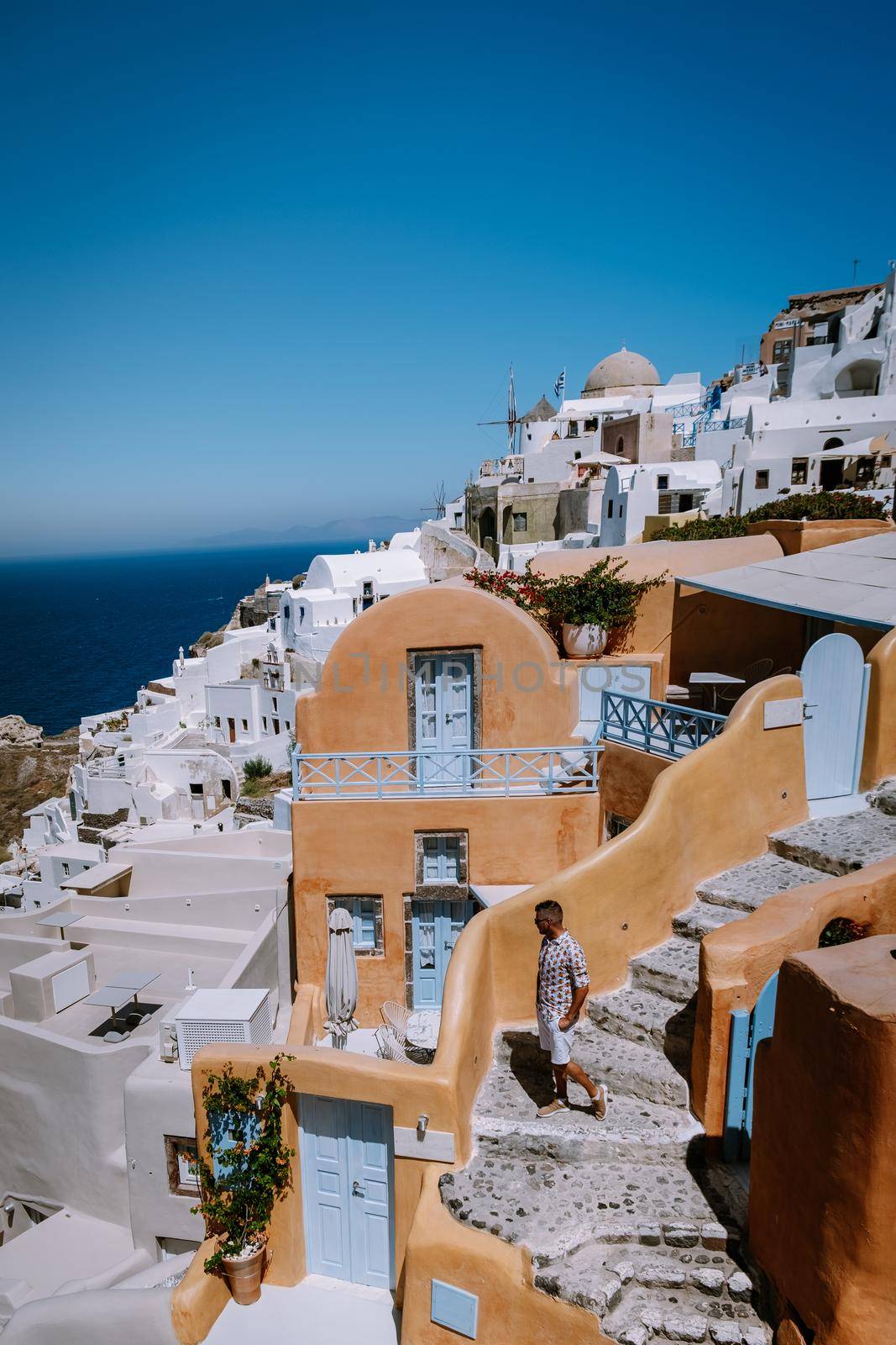 Santorini Greece, young man on luxury vacation at the Island of Santorini watching sunrise by the blue dome church and whitewashed village of Oia Santorini Greece during sunrise, men and woman on holiday in Greece by fokkebok