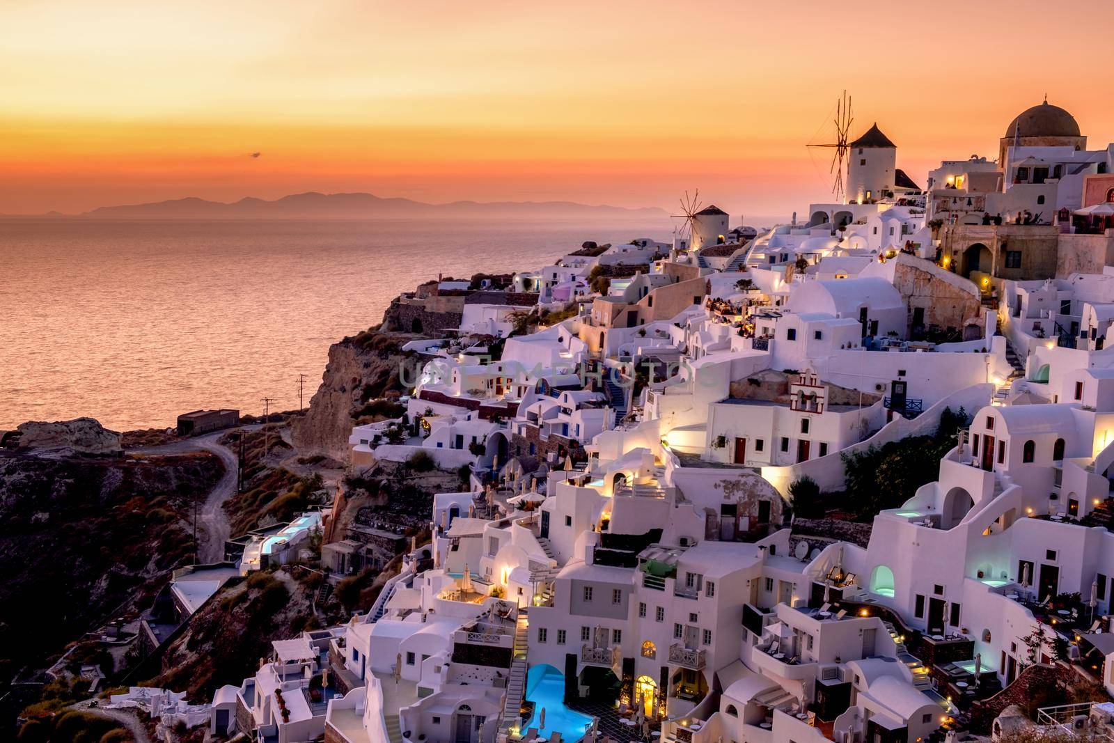 Sunset at the Island Of Santorini Greece, beautiful whitewashed village Oia with church and windmill during sunset by fokkebok