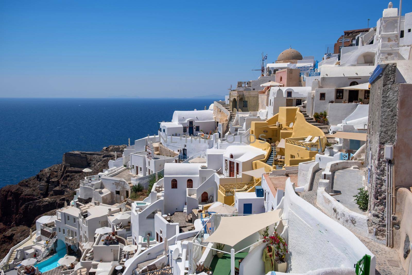 Sunset at the Island Of Santorini Greece, beautiful whitewashed village Oia with church and windmill during sunset by fokkebok