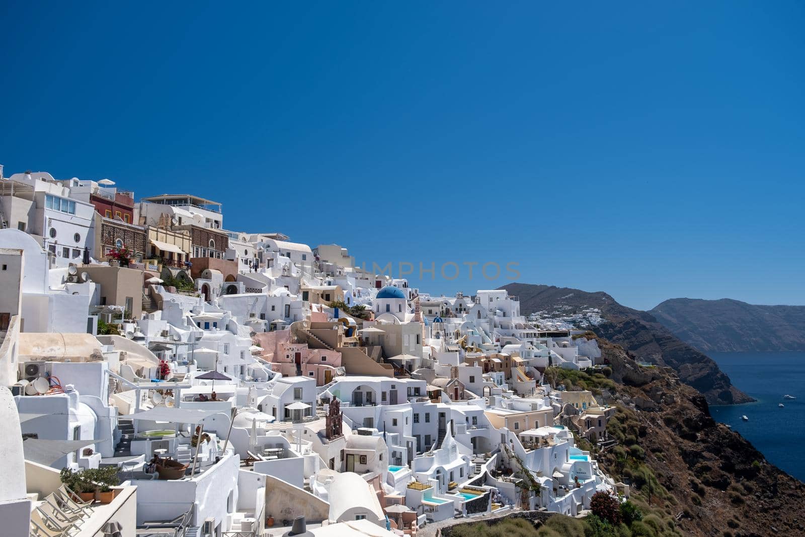 Santorini, Greece. Picturesq view of traditional cycladic Santorini houses on small street with flowers in foreground. Location: Oia village, Santorini, Greece. Vacations background Europe