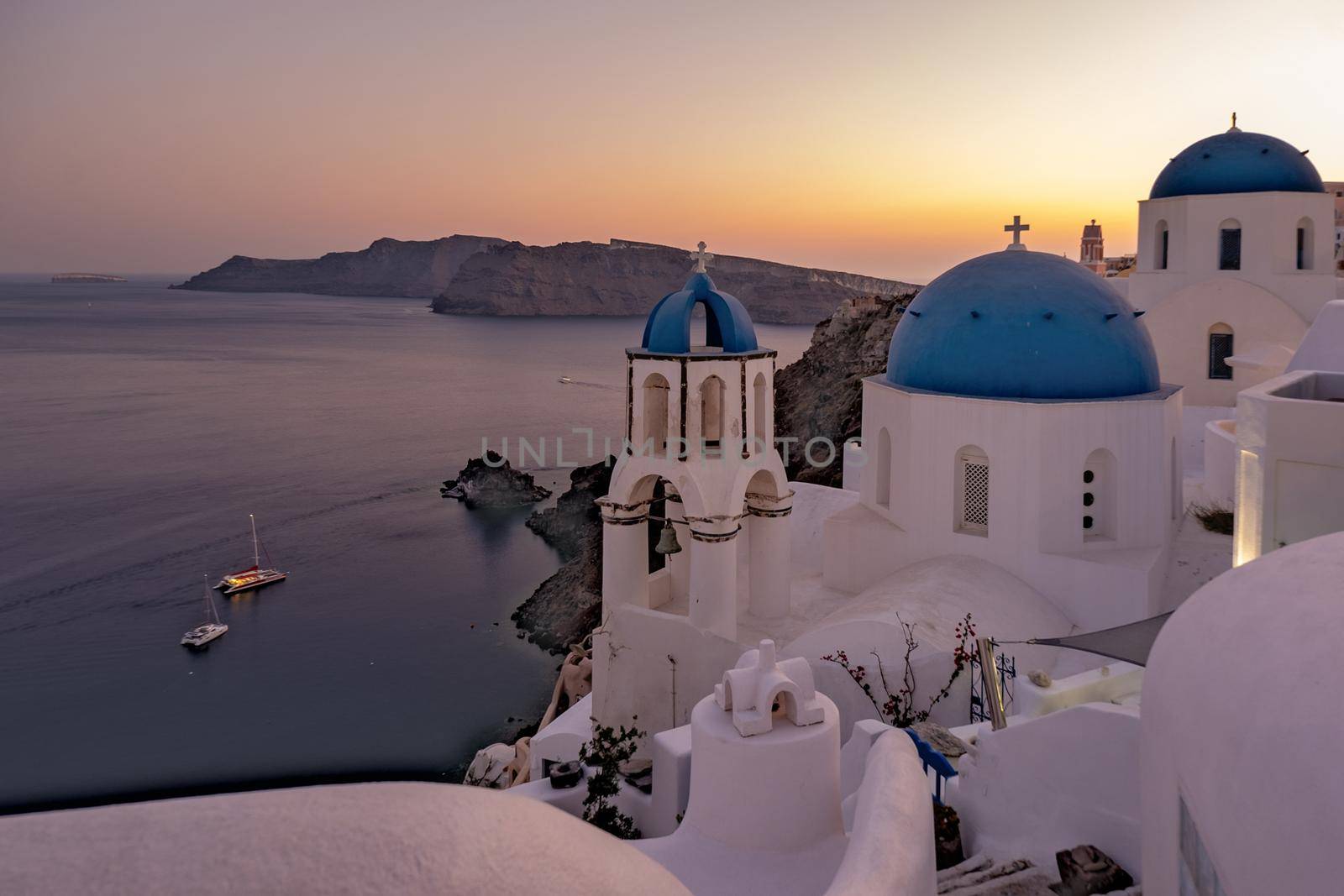 Sunset at the Island Of Santorini Greece, beautiful whitewashed village Oia with church and windmill during sunset by fokkebok