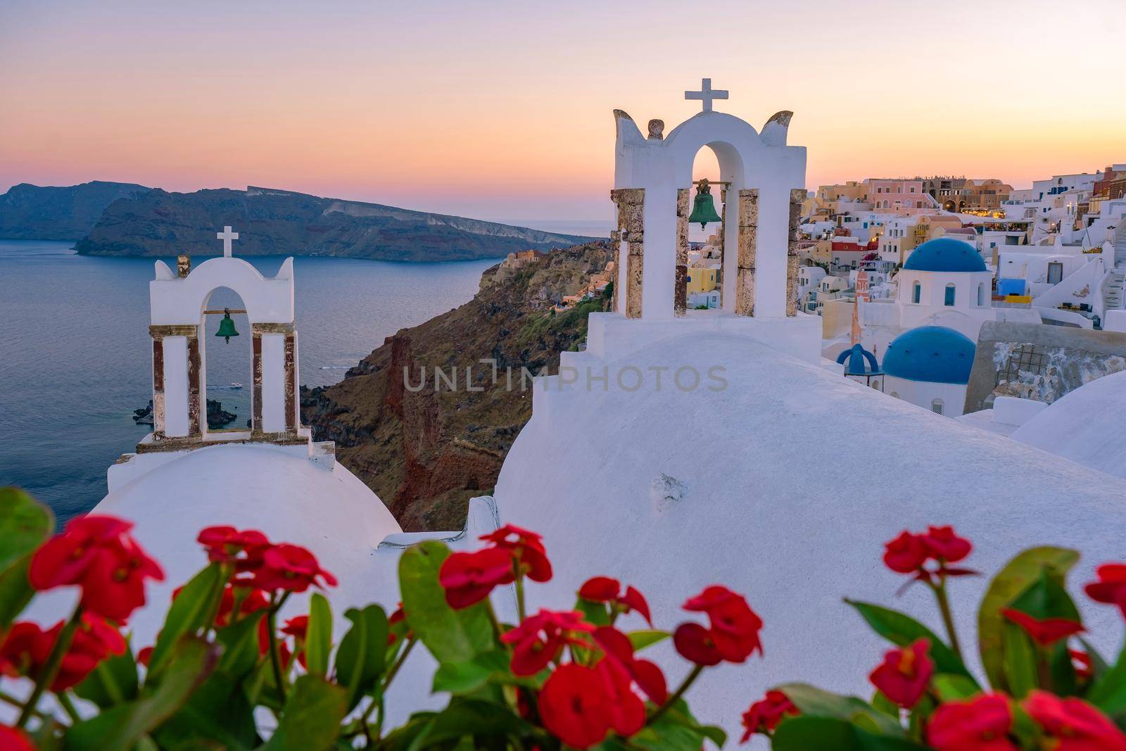 Sunset at the Island Of Santorini Greece, beautiful whitewashed village Oia with church and windmill during sunset, streets of Oia Santorini during summer vacation at the Greek Island