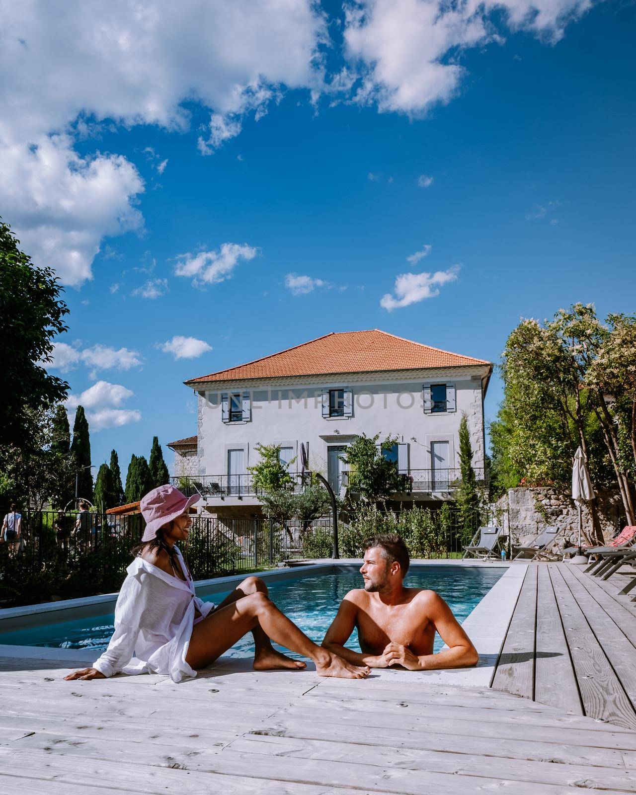 French vacation home with wooden deck and swimming pool in the Ardeche France. Couple relaxing by the pool with wooden deck during luxury vacation at an holiday home in South of France by fokkebok