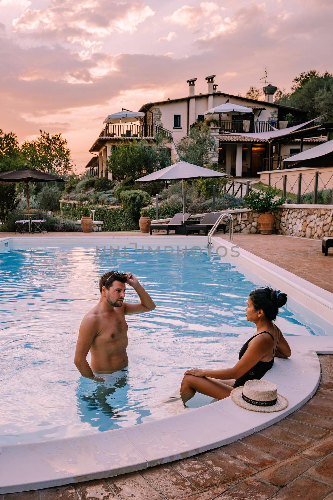 Luxury country house with swimming pool in Italy. Pool and old farm house during sunset central Italy. Couple on Vacation at luxury villa in Italy, men and woman watching sunset