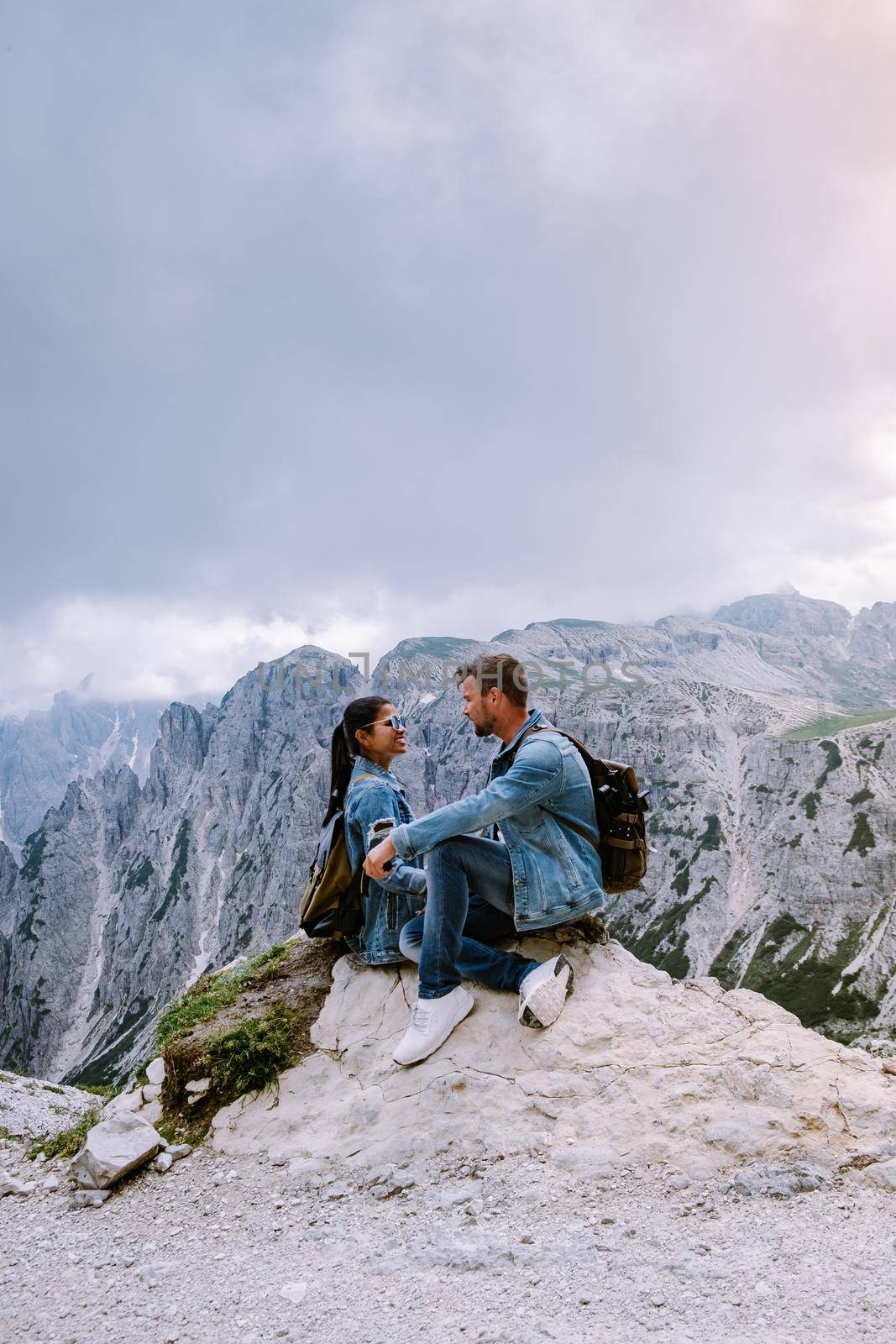 couple hiking in the italian dolomites during foggy weather with clouds, Stunning view to Tre Cime peaks in Dolomites, Italy by fokkebok