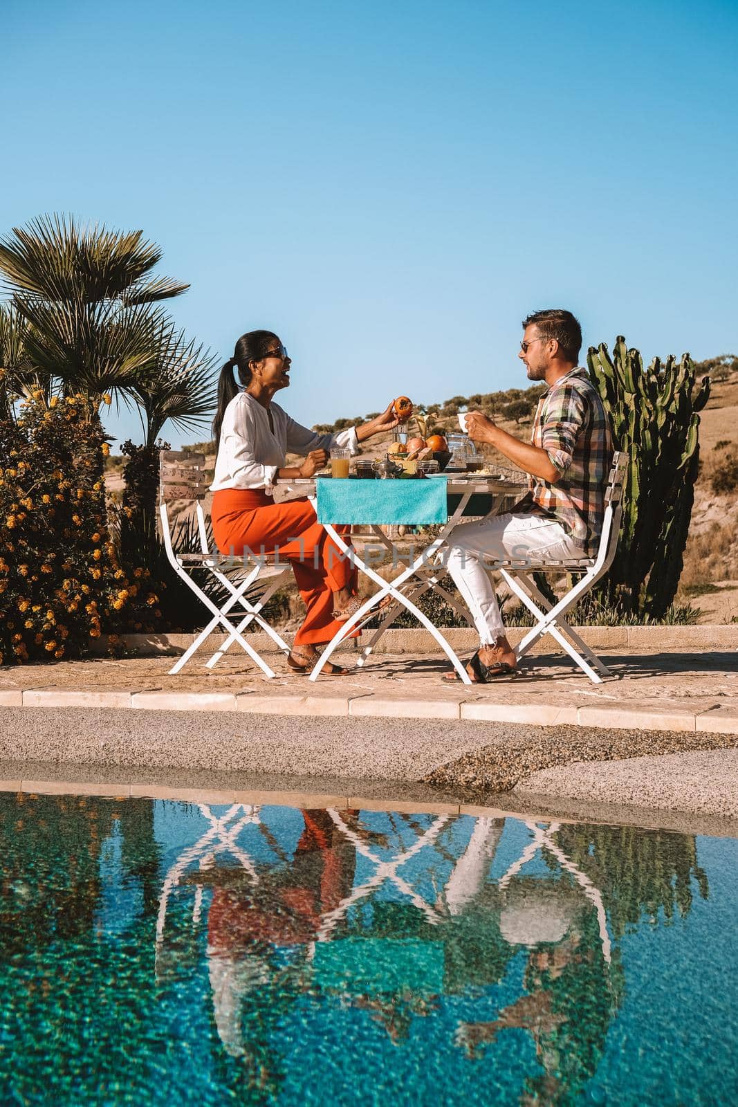 couple having breakfast in the garden looking out over the hills of Sicily, men and woman of mid-age on vacation having breakfast outside