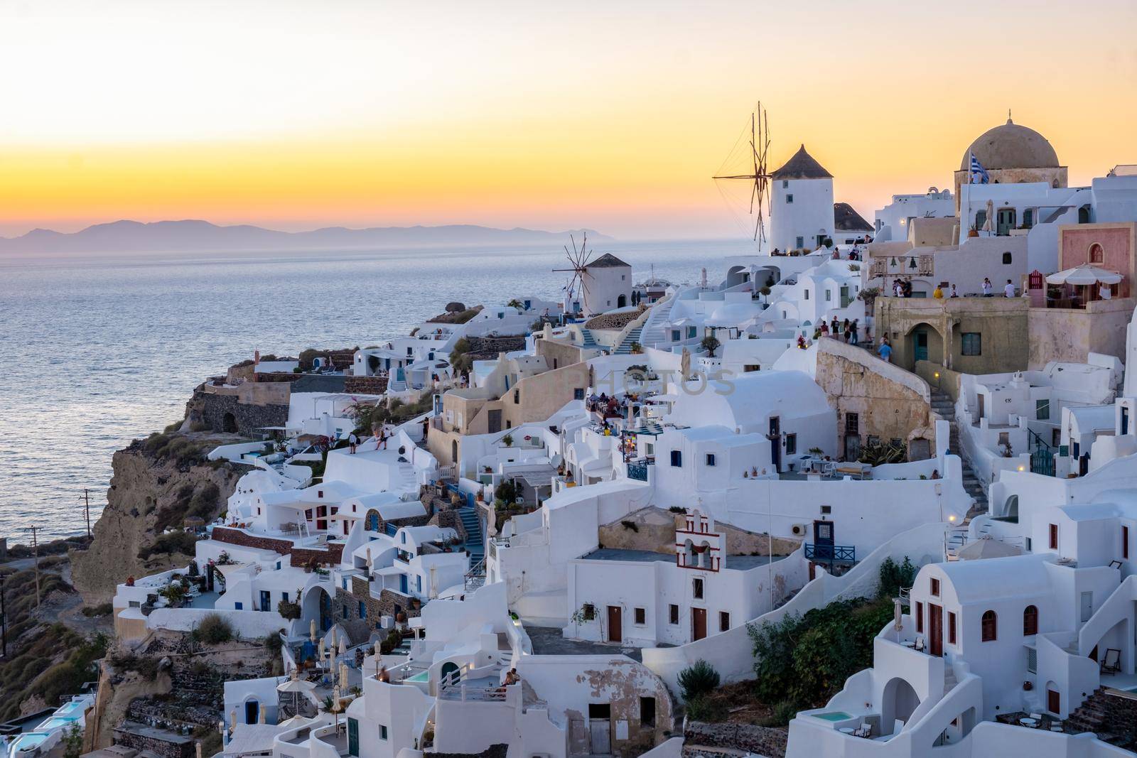 Sunset at the Island Of Santorini Greece, beautiful whitewashed village Oia with church and windmill during sunset by fokkebok