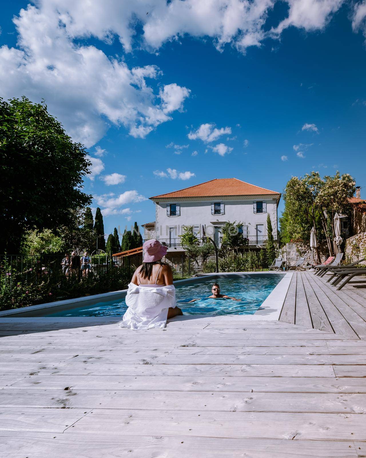 French vacation home with wooden deck and swimming pool in the Ardeche France. Couple relaxing by the pool with wooden deck during luxury vacation at an holiday home in South of France by fokkebok