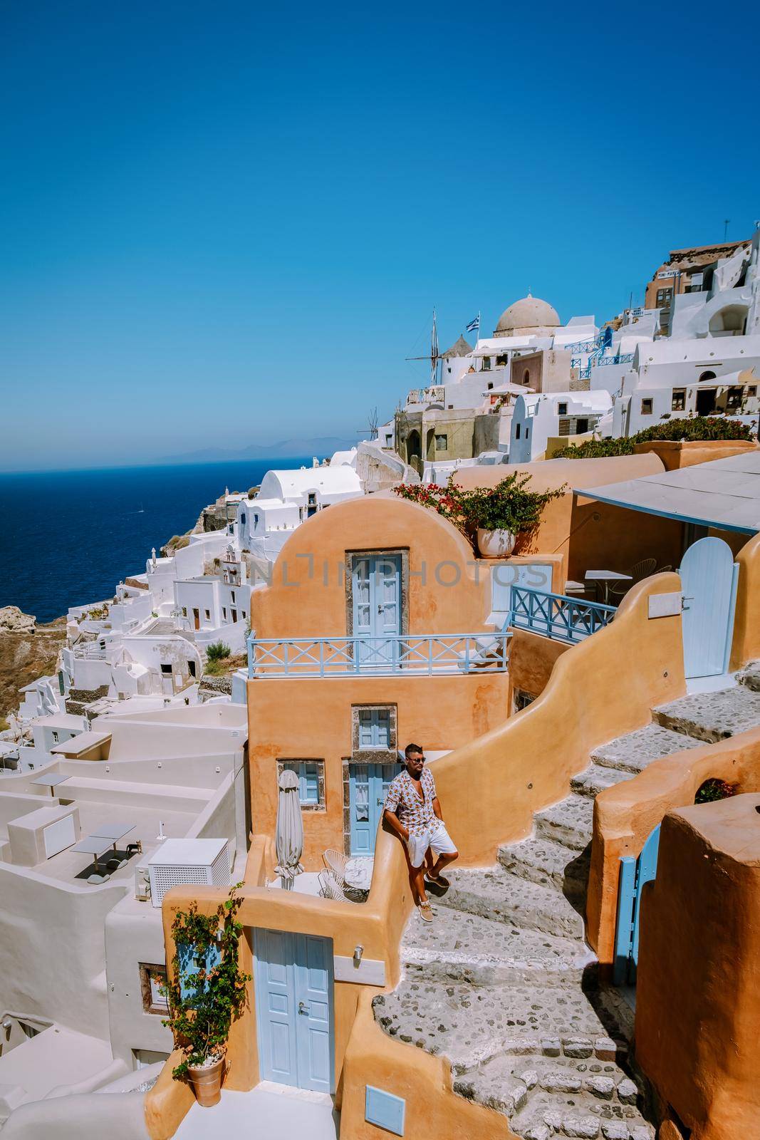 Santorini Greece, young man on luxury vacation at the Island of Santorini watching sunrise by the blue dome church and whitewashed village of Oia Santorini Greece during sunrise, men and woman on holiday in Greece by fokkebok