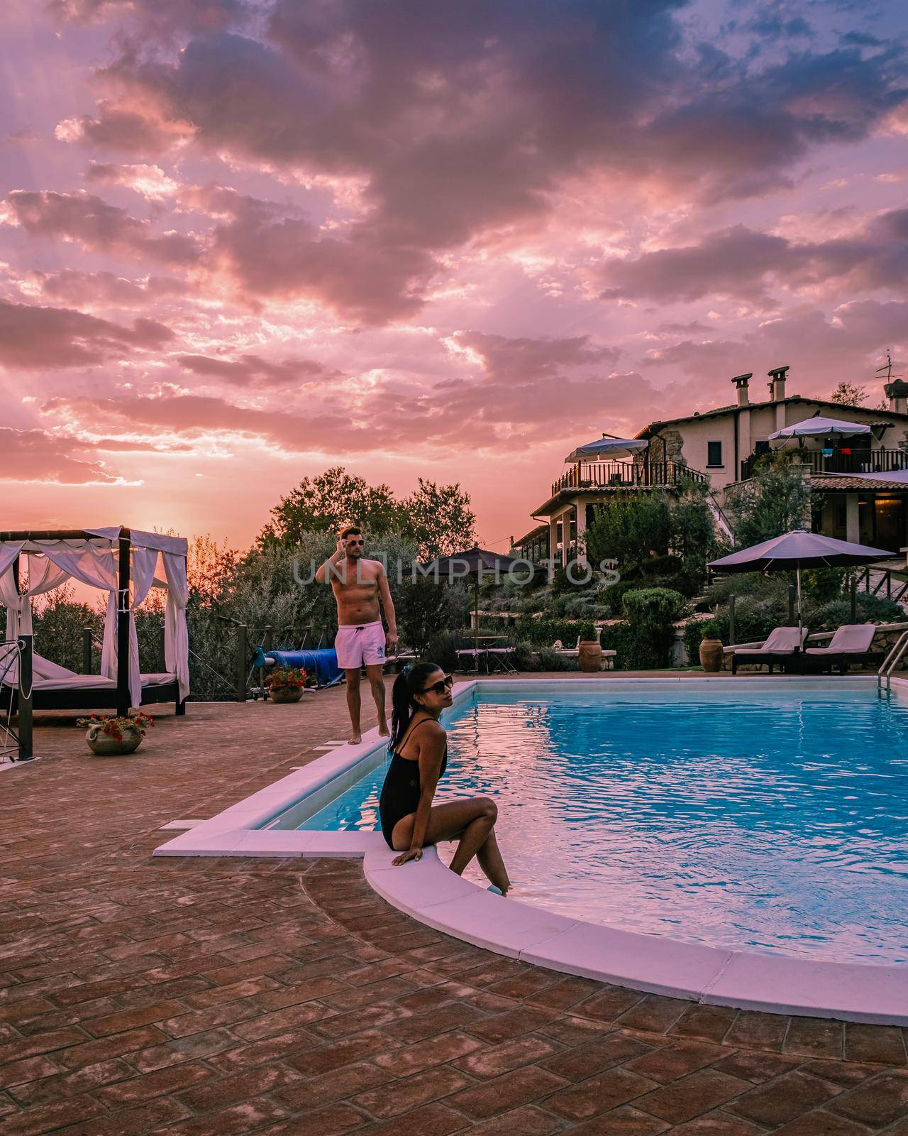 Luxury country house with swimming pool in Italy. Pool and old farm house during sunset central Italy. Couple on Vacation at luxury villa in Italy, men and woman watching sunset