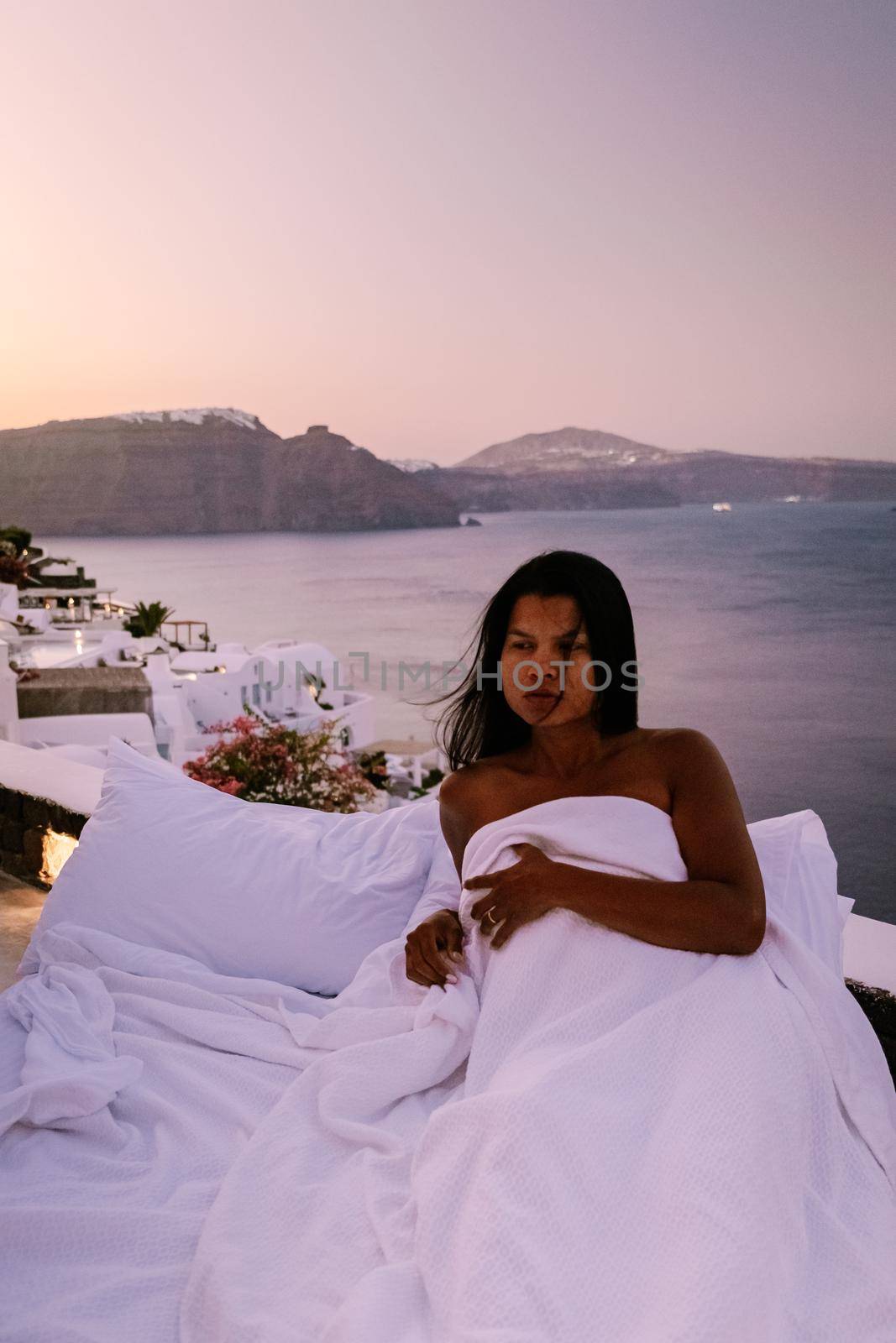 Santorini Greece, young woman on luxury vacation at the Island of Santorini watching sunrise by the blue dome church and whitewashed village of Oia Santorini Greece during sunrise, men and woman on holiday in Greece by fokkebok