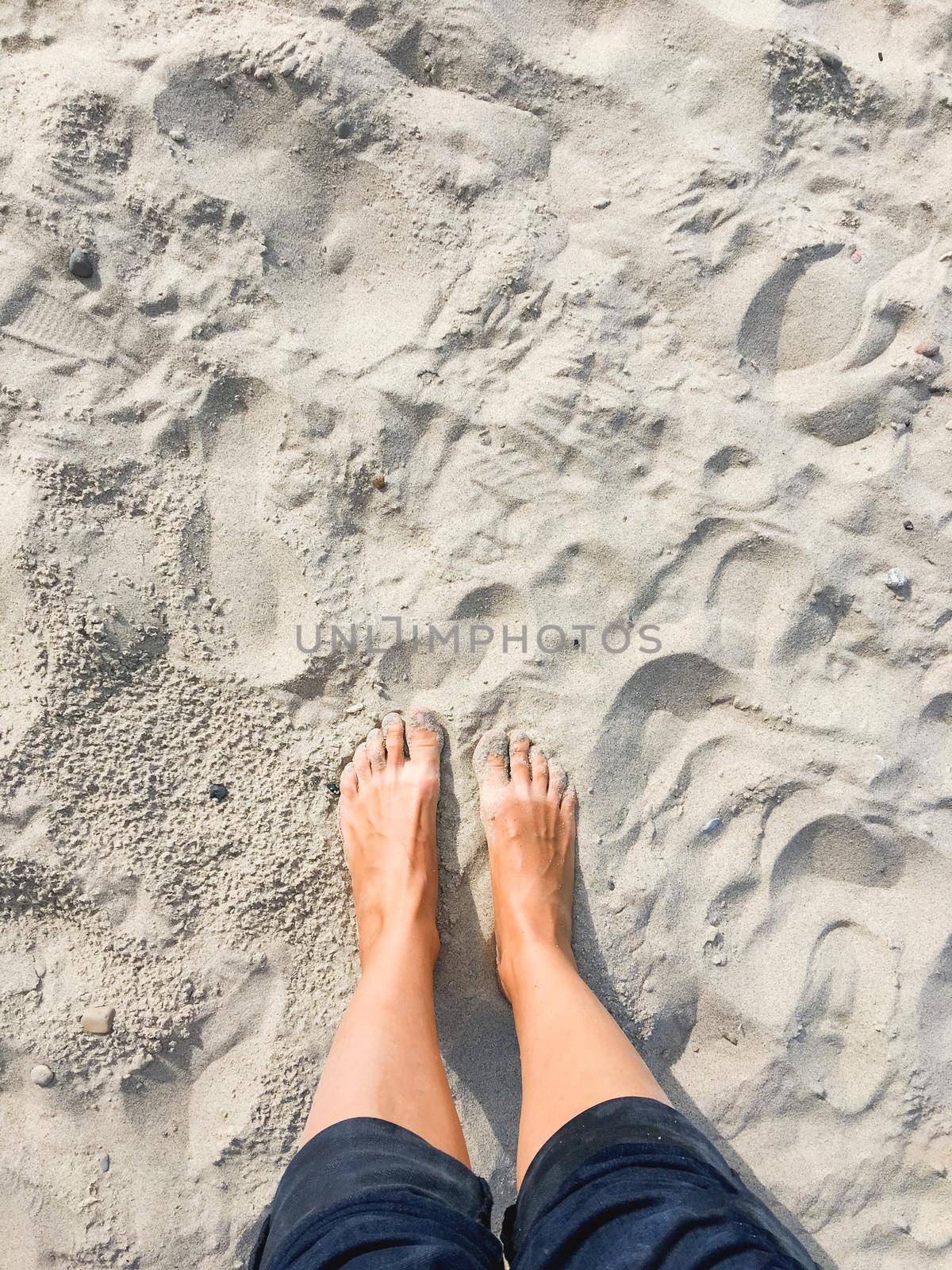 Woman stands barefoot on beach sand. Long-awaited vacation. Journey to countries with warm climate. Tactile pleasure. by aksenovko