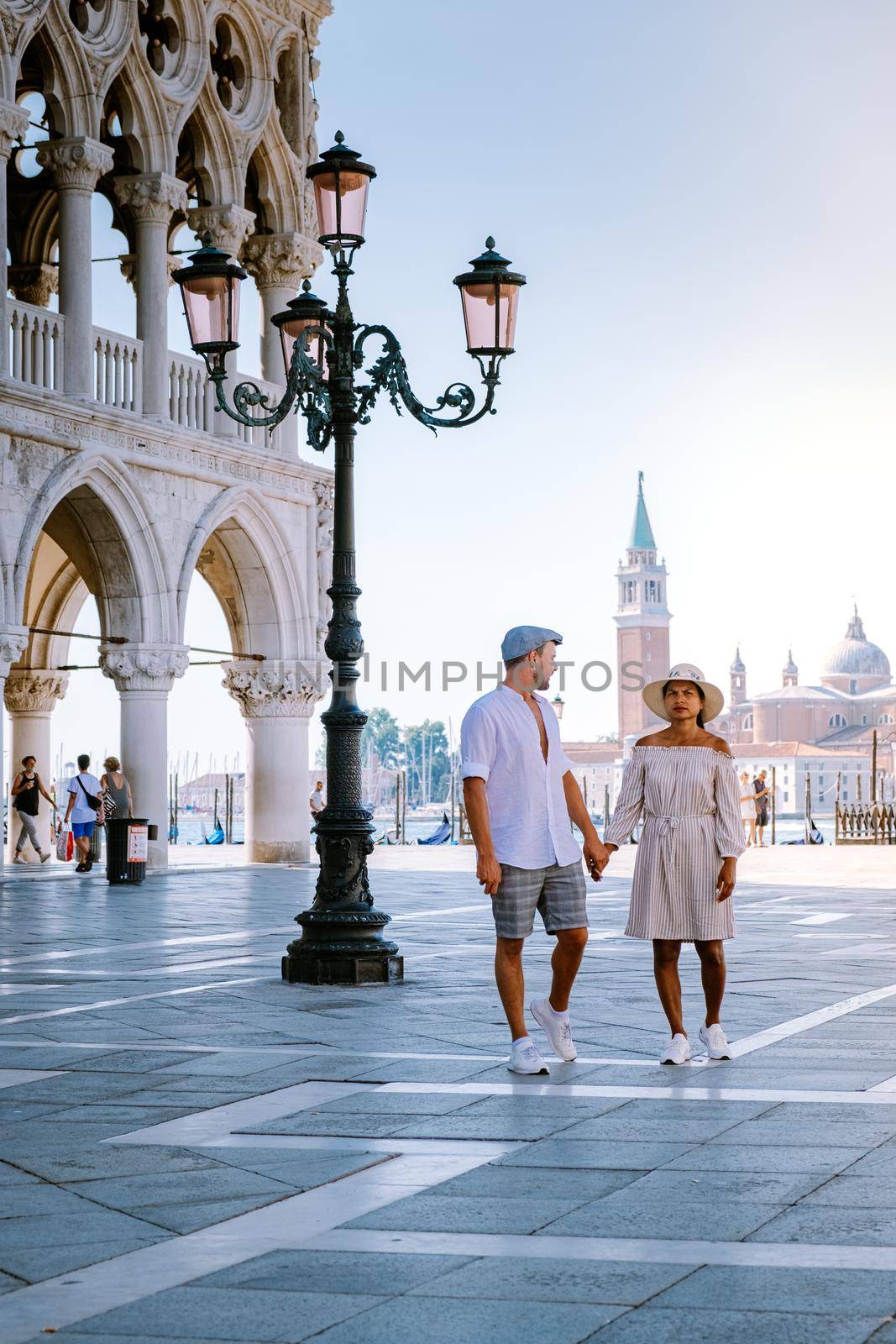 couple on a city trip in Venice, view of piazza San Marco, Doge's Palace Palazzo Ducale in Venice, Italy. Architecture and landmark of Venice. Sunrise cityscape of Venice by fokkebok