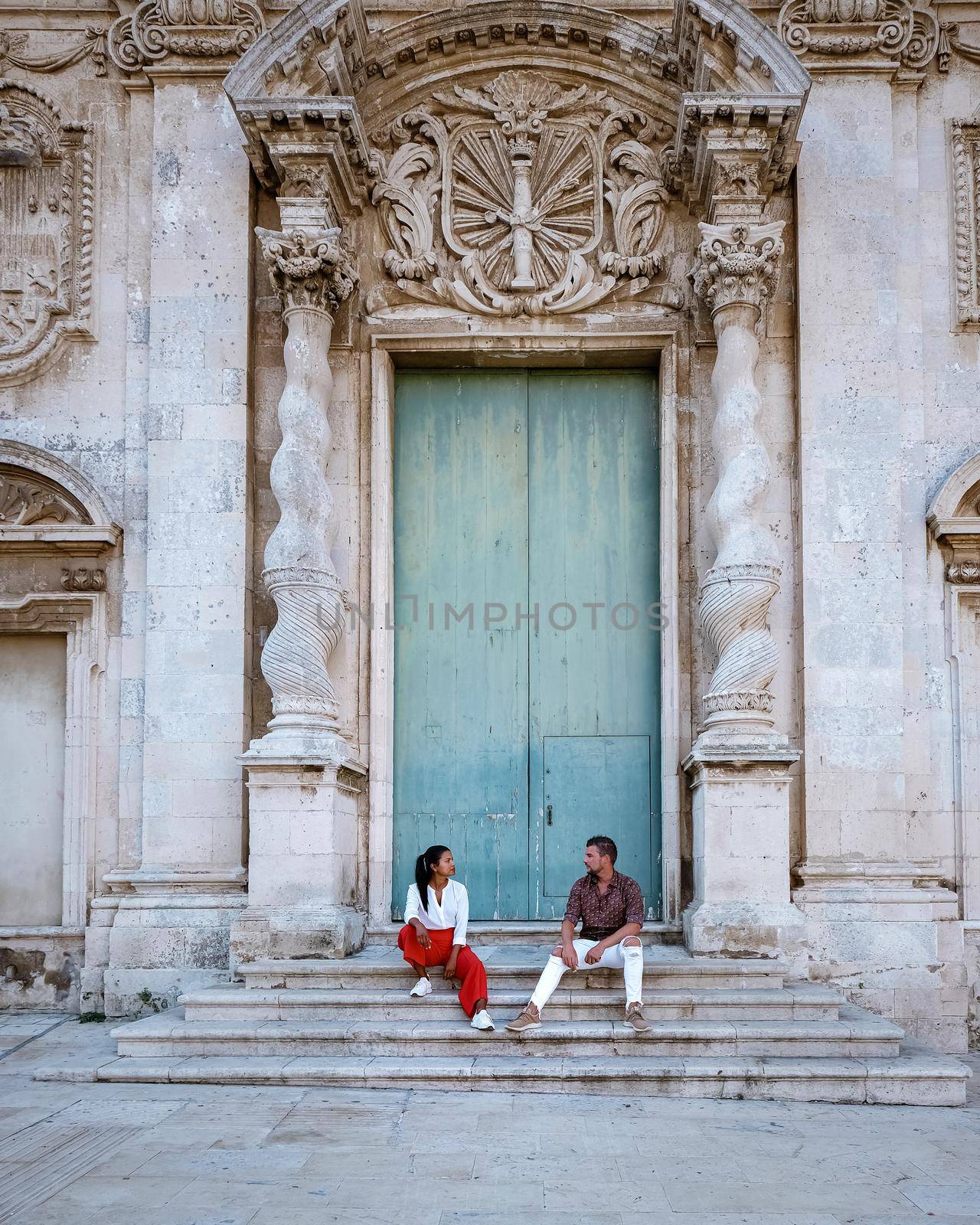couple men and woman on citytrip Ortigia in Syracuse in the Morning. Travel Photography from Syracuse, Italy on the island of Sicily. Cathedral Plaza and market with people whear face protection during the 2020 pandemic by fokkebok