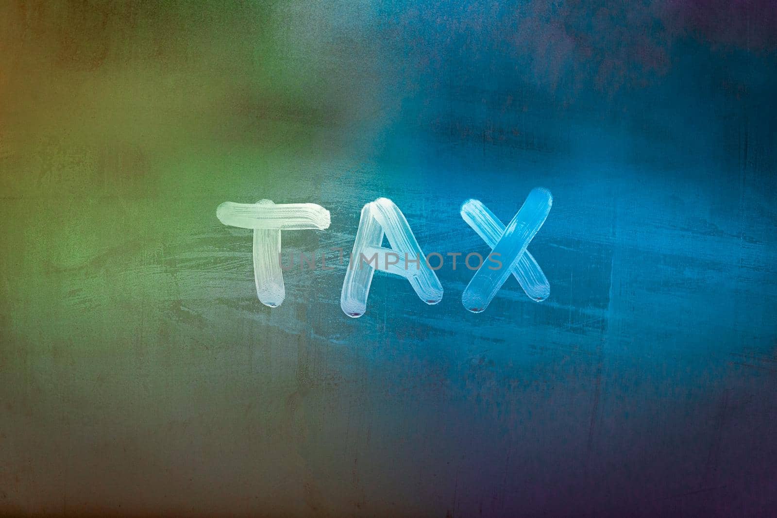 word tax hadwritten on night wet window glass surface with green and orange colors in blurry background