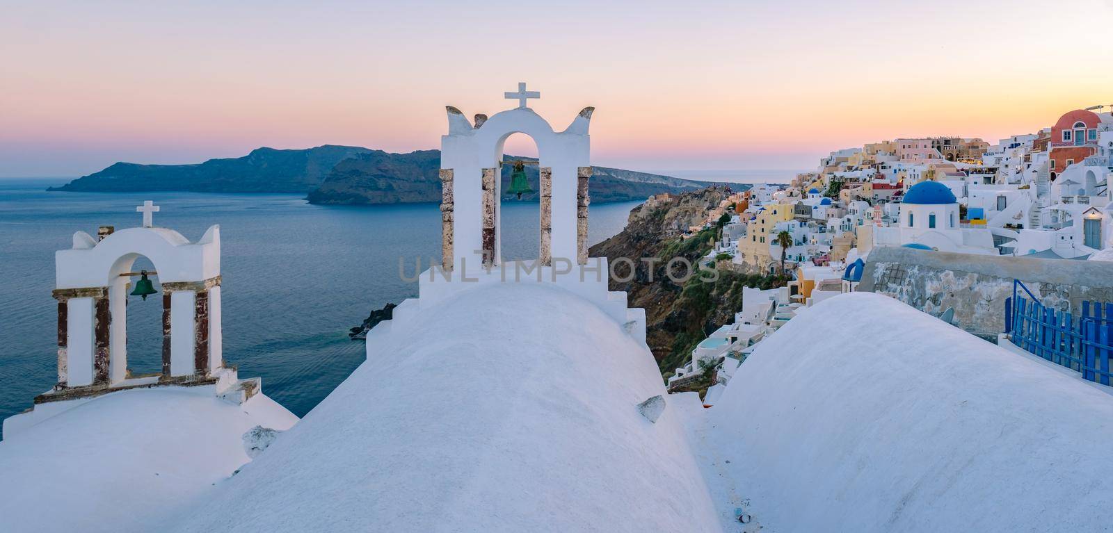 Sunset at the Island Of Santorini Greece, beautiful whitewashed village Oia with church and windmill during sunset, streets of Oia Santorini during summer vacation at the Greek Island