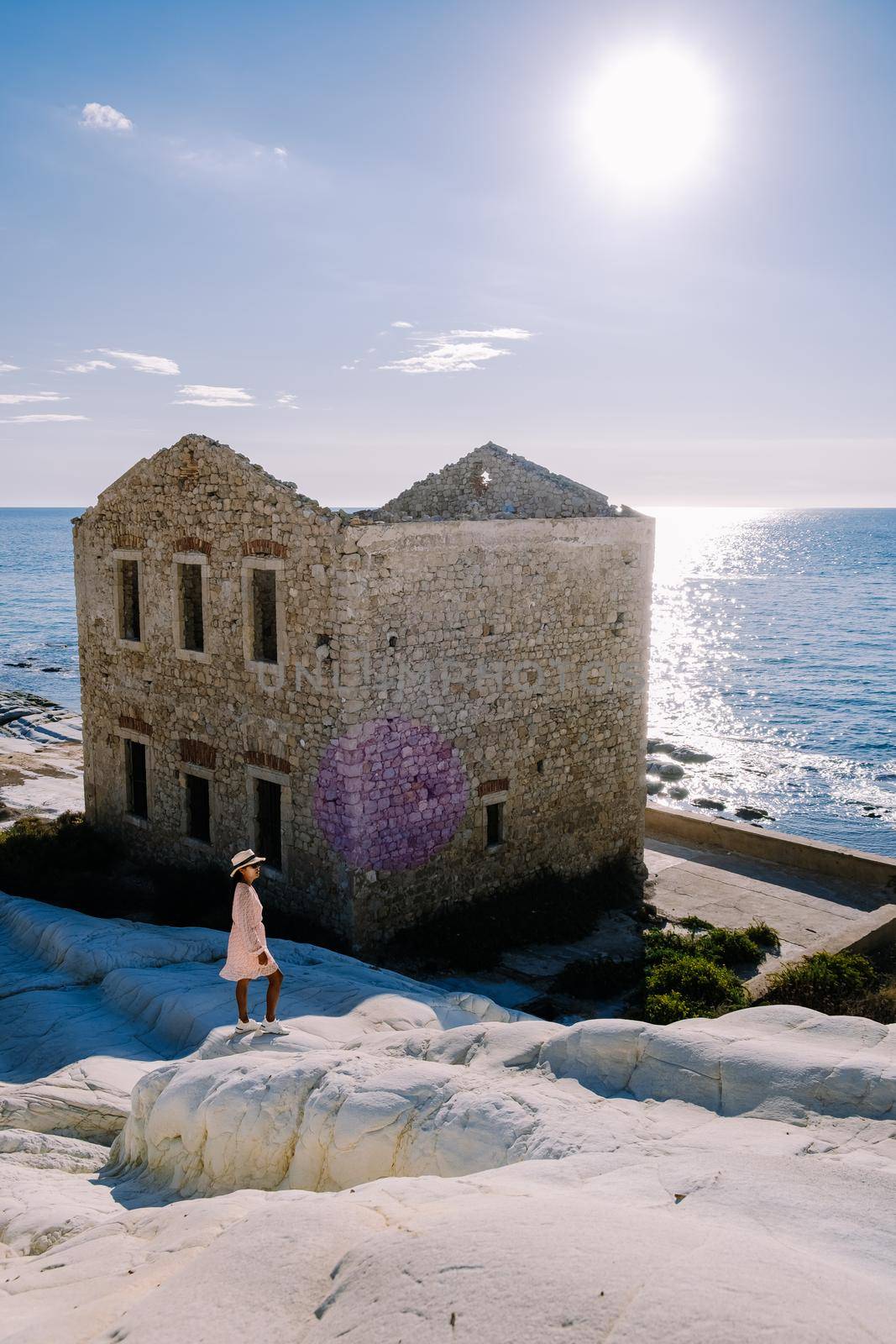 Punta Bianca, Agrigento in Sicily Italy White beach with old ruins of an abandoned stone house on white cliffs. Sicilia Italy, a woman walking on the beach