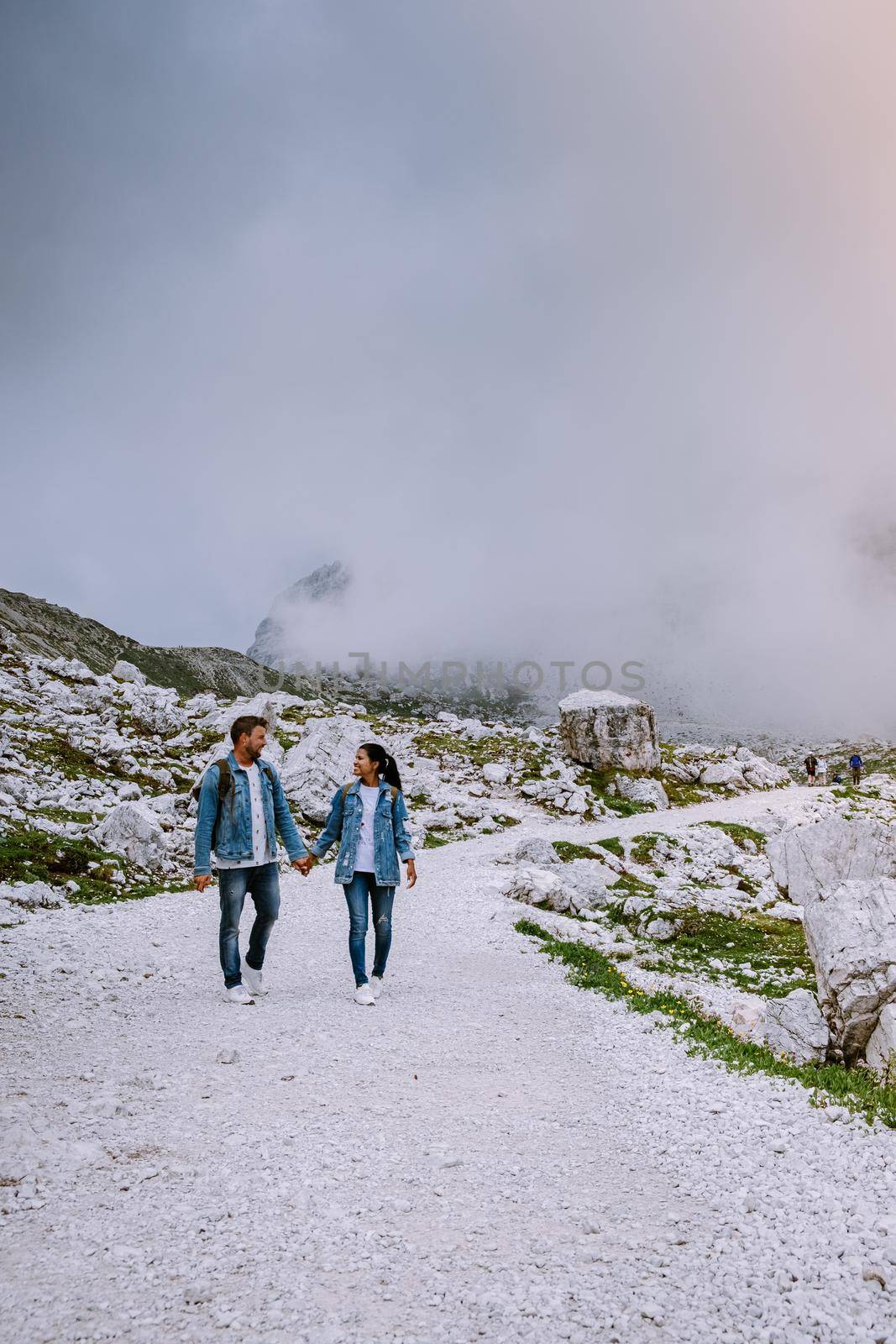 couple hiking in the italian dolomites during foggy weather with clouds, Stunning view to Tre Cime peaks in Dolomites, Italy. Europe