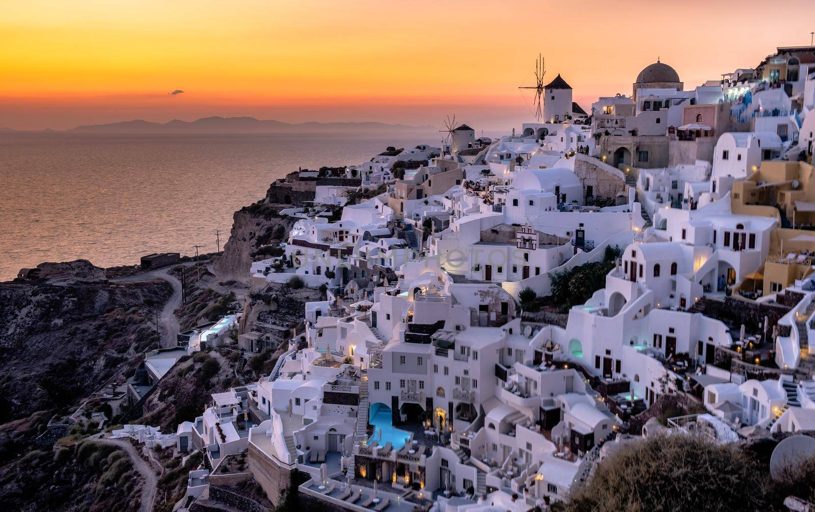 Sunset at the Island Of Santorini Greece, beautiful whitewashed village Oia with church and windmill during sunset by fokkebok