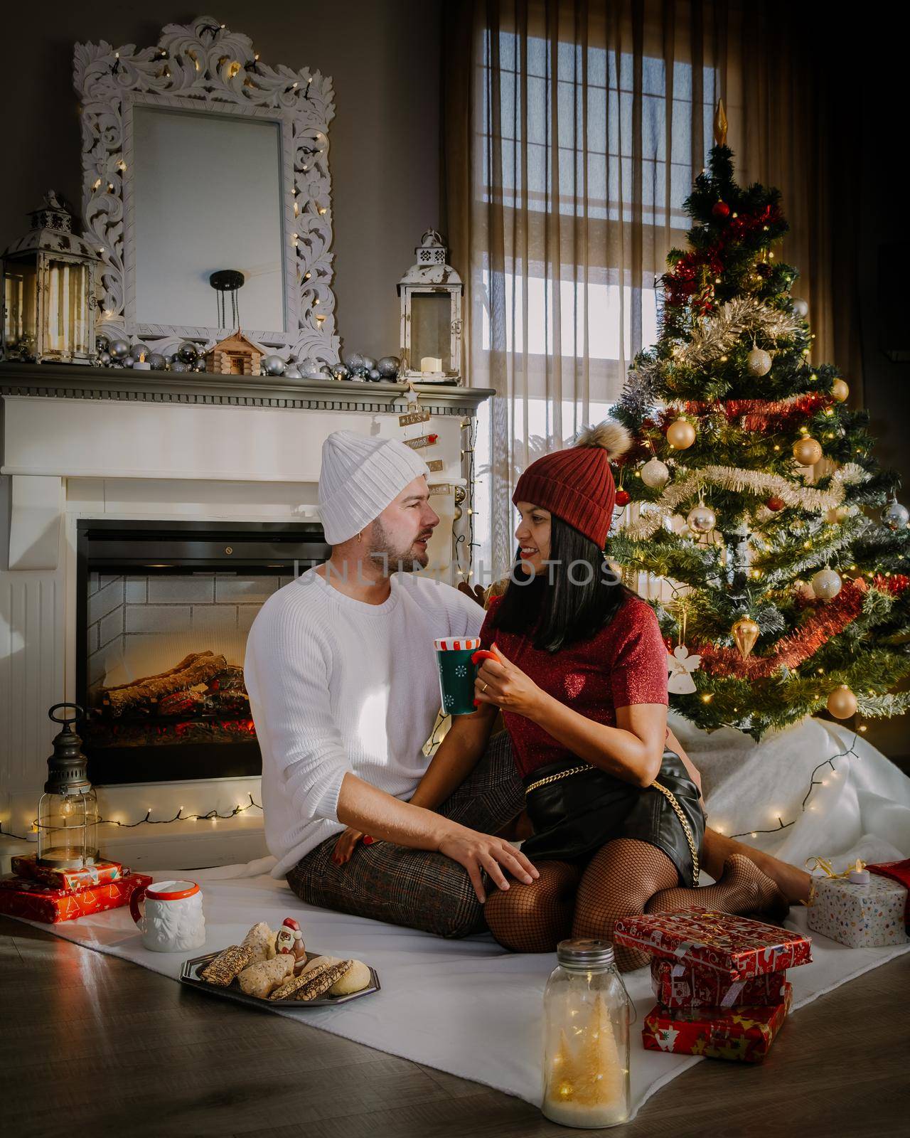 Family sitting on a floor. Couple near christmas tree, Christmas couple with present by fokkebok