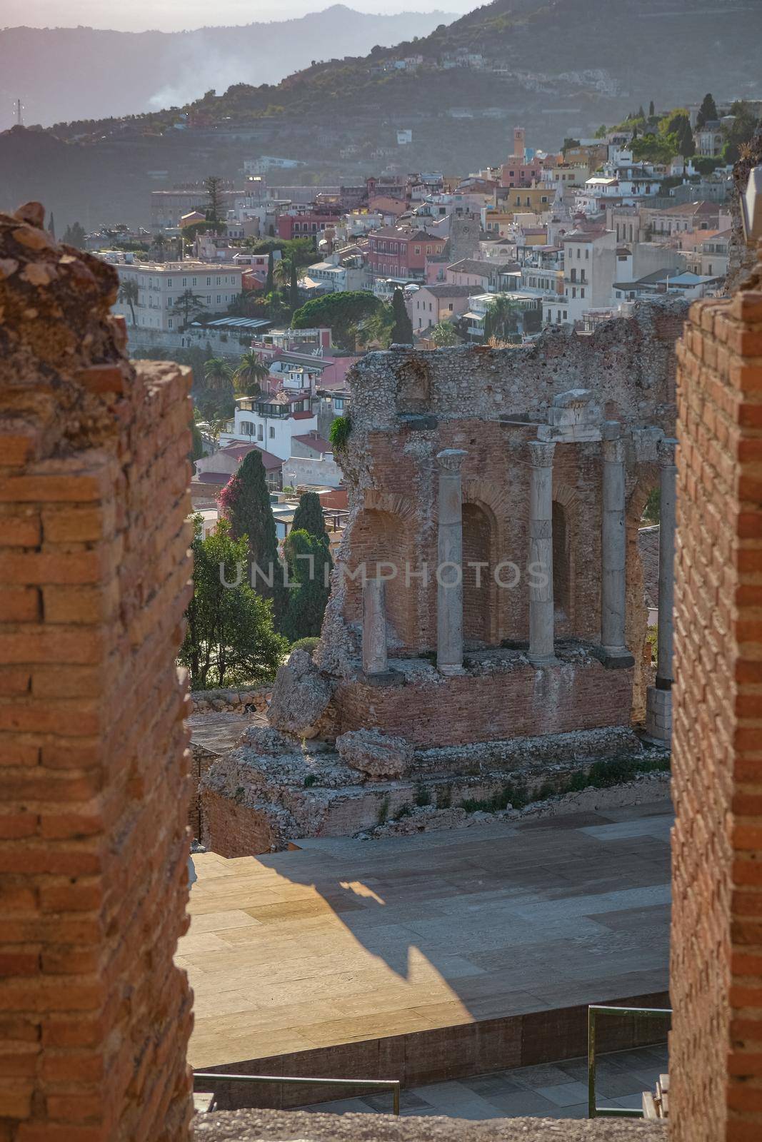 Ruins of Ancient Greek theatre in Taormina on background of Etna Volcano, Italy. Taormina located in Metropolitan City of Messina, on east coast of island of Sicily Europe