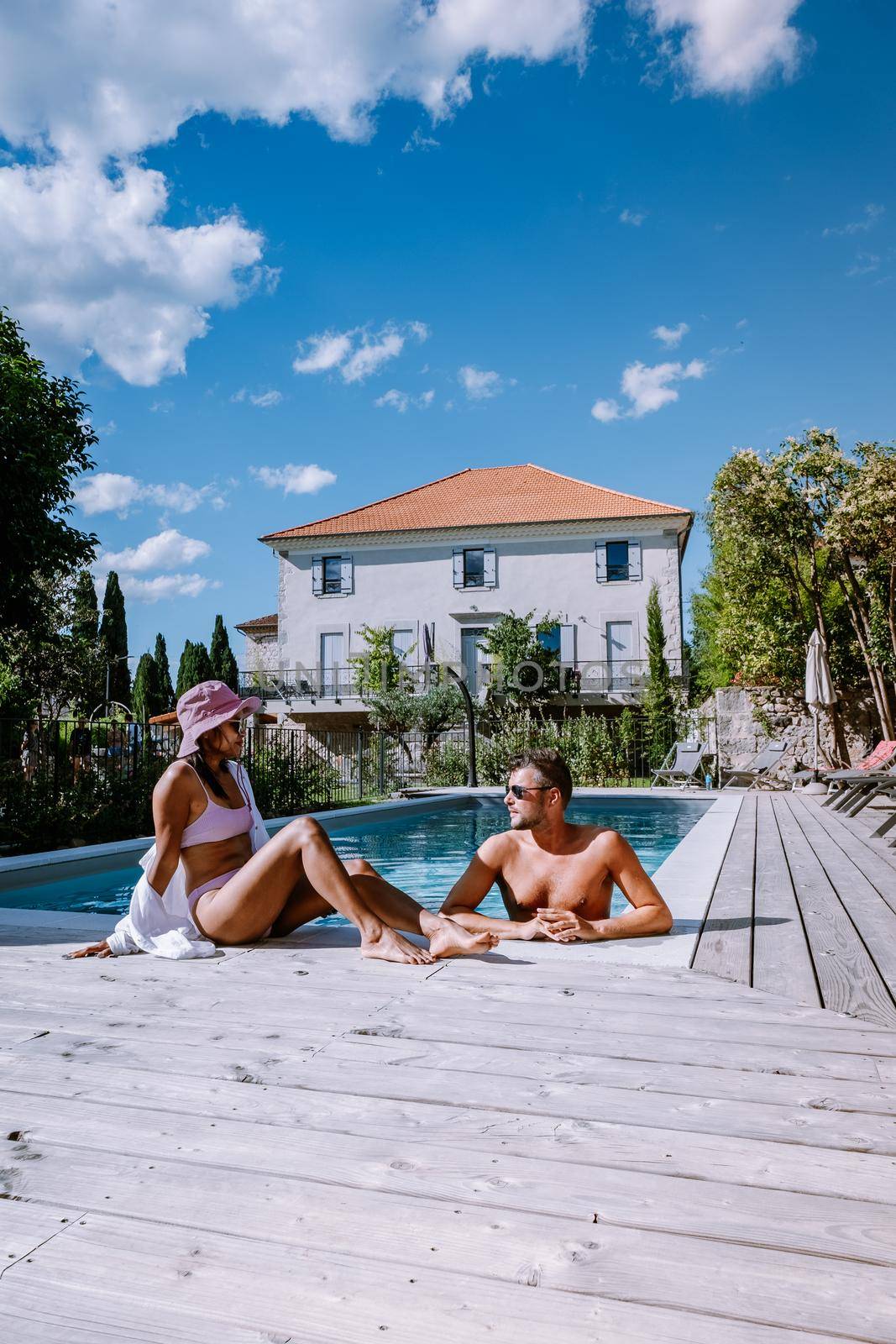 French vacation home with wooden deck and swimming pool in the Ardeche France. Couple relaxing by the pool with wooden deck during luxury vacation at an holiday home in South of France by fokkebok