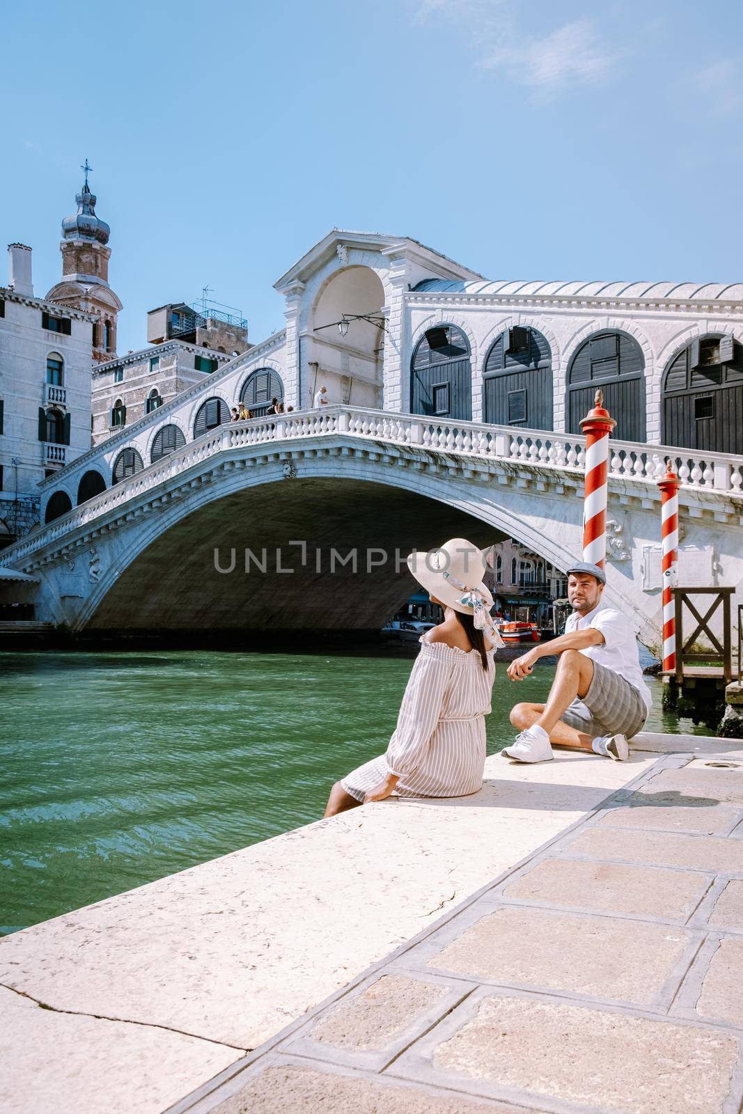 Venice Italy couple men and woman on a city trip at Venice, men and woman at waterfront looking at the famous Rialto bridge in Venice Italy. Europe