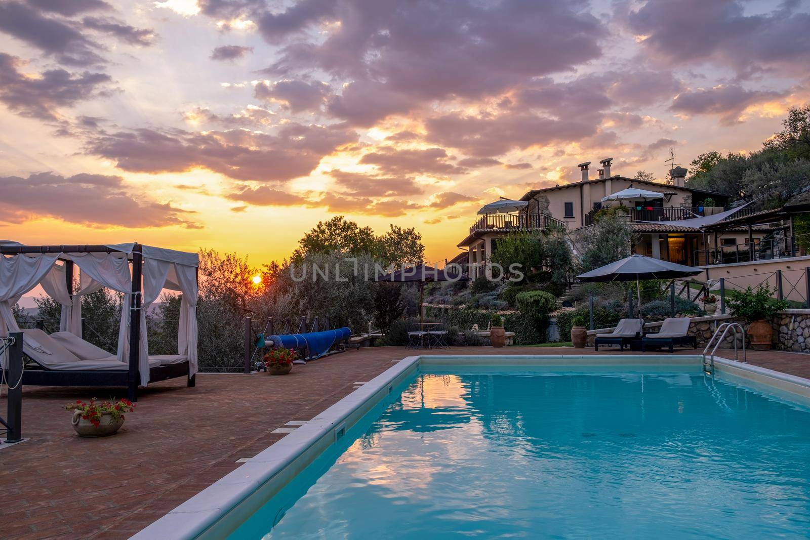 Luxury country house with swimming pool in Italy. Pool and old farm house during sunset central Italy