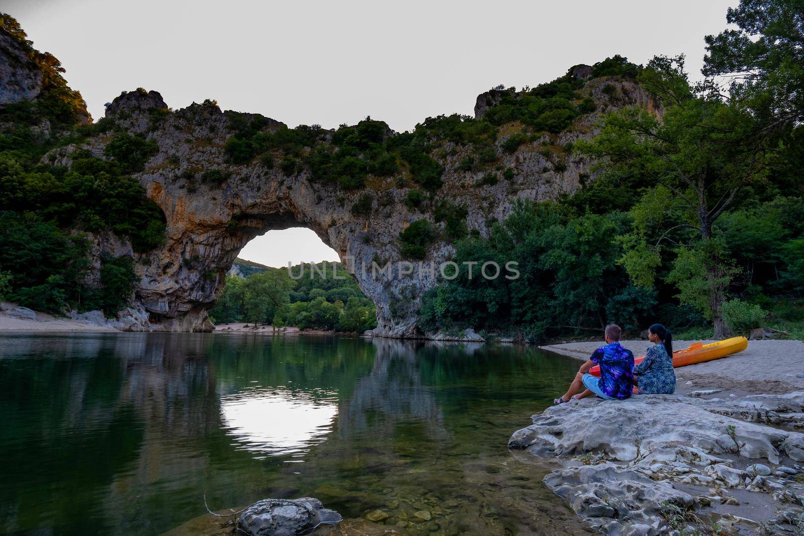 couple on the beach by the river in the Ardeche France Pont d Arc, Ardeche France,view of Narural arch in Vallon Pont D'arc in Ardeche canyon in France by fokkebok