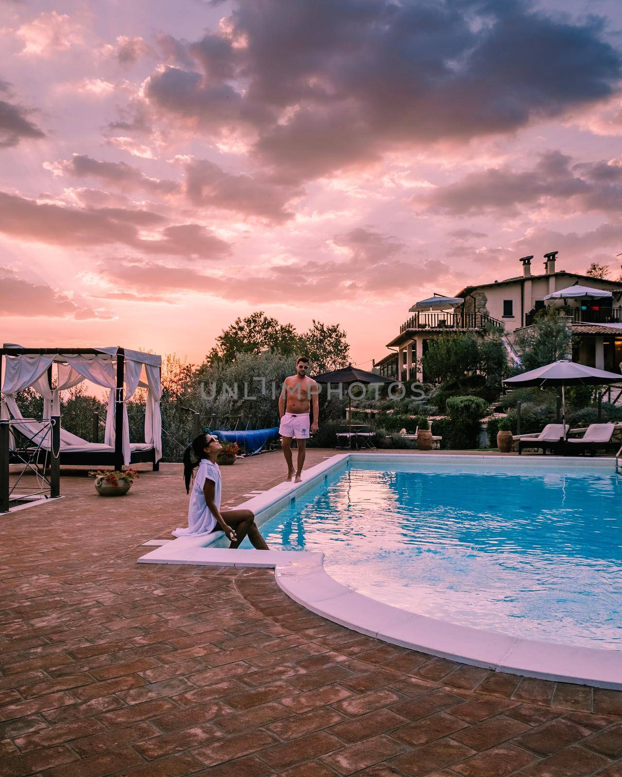 Luxury country house with swimming pool in Italy. Pool and old farm house during sunset central Italy. Couple on Vacation at luxury villa in Italy, men and woman watching sunset