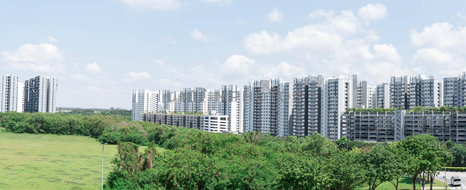 Panorama shot of HDB condominiums in Singapore. Green forest park and blue sky with clouds
