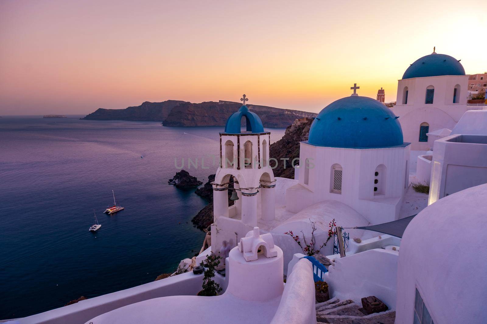 Sunset at the Island Of Santorini Greece, beautiful whitewashed village Oia with church and windmill during sunset by fokkebok