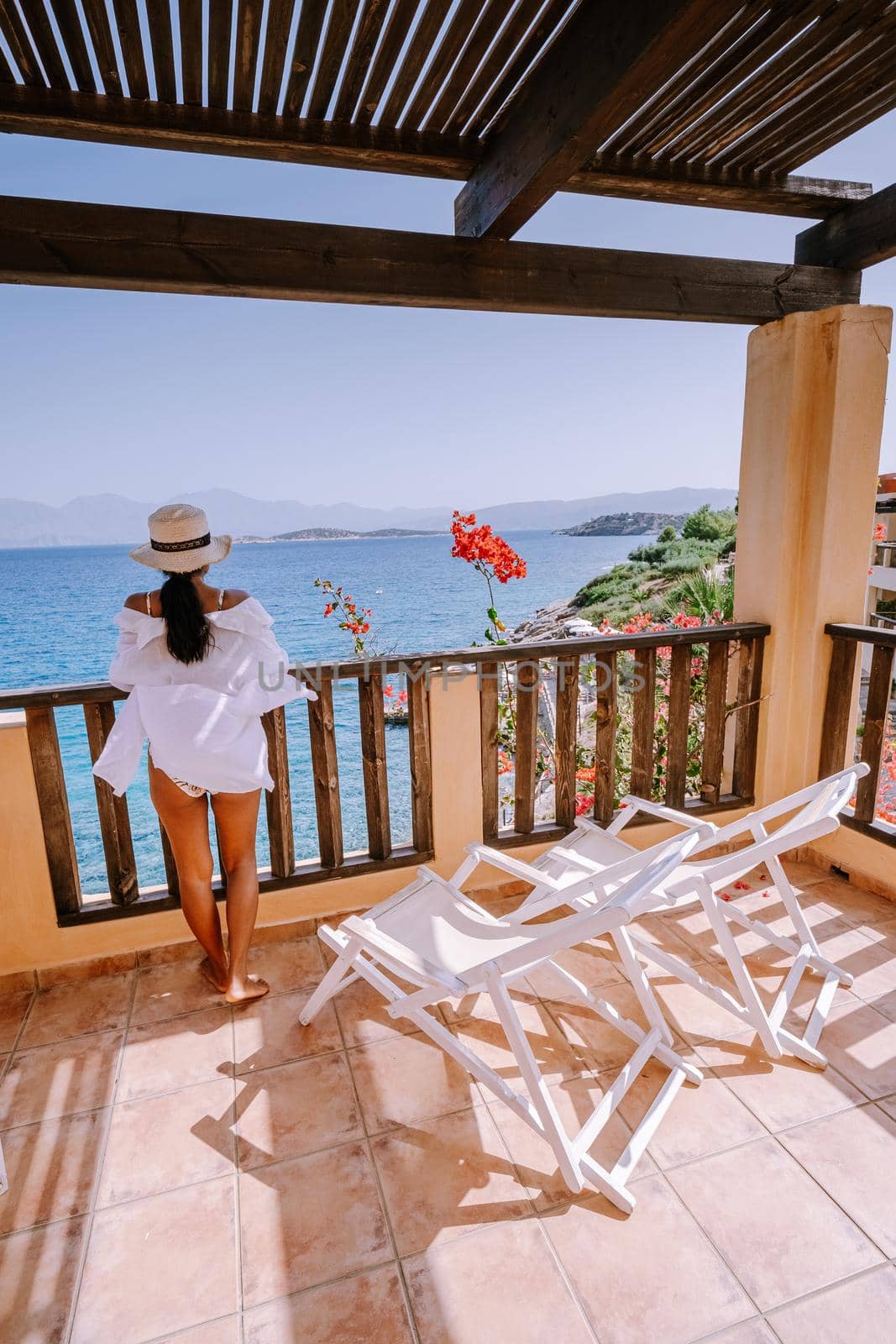 woman on balcony on holiday luxury vacation looking out over the ocean of Crete Greece Europe