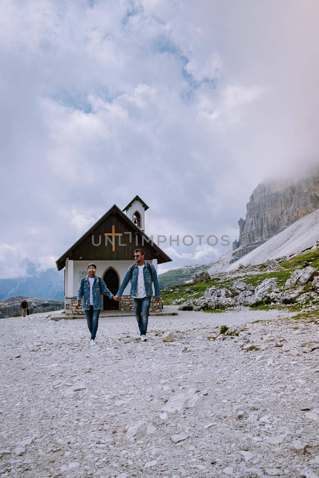 couple hiking in the italian dolomites during foggy weather with clouds, Stunning view to Tre Cime peaks in Dolomites, Italy by fokkebok