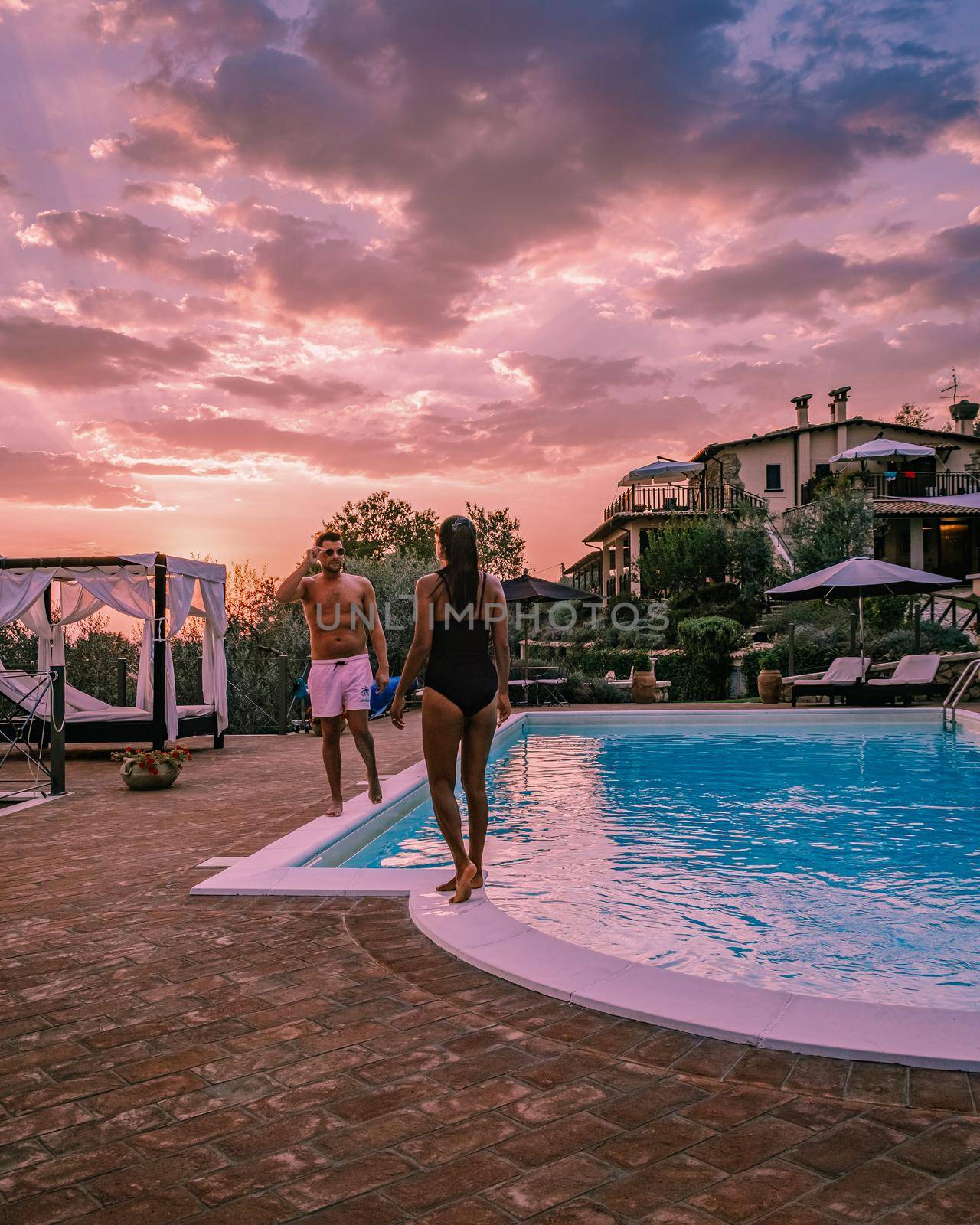 Luxury country house with swimming pool in Italy. Pool and old farm house during sunset central Italy. Couple on Vacation at luxury villa in Italy, men and woman watching sunset