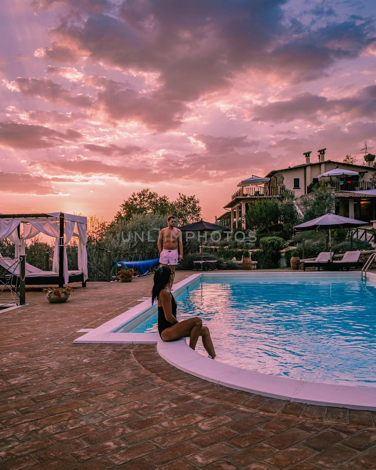 Luxury country house with swimming pool in Italy. Pool and old farm house during sunset central Italy. Couple on Vacation at luxury villa in Italy, men and woman watching sunset