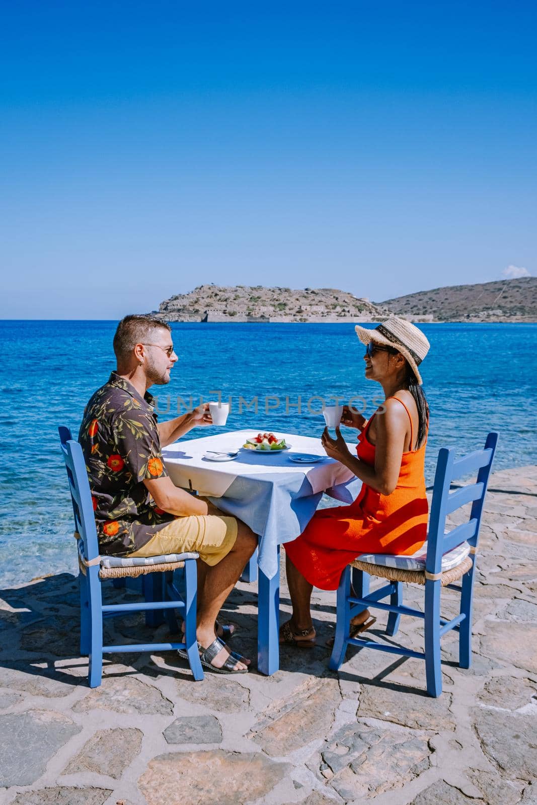 Plaka Lassithi with is traditional blue table and chairs and the beach in Crete Greece by fokkebok