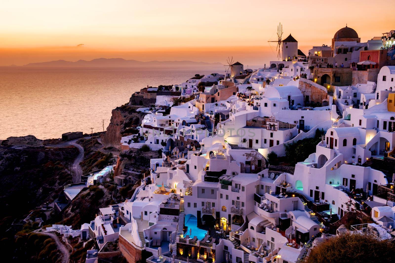 Sunset at the Island Of Santorini Greece, beautiful whitewashed village Oia with church and windmill during sunset, streets of Oia Santorini during summer vacation at the Greek Island