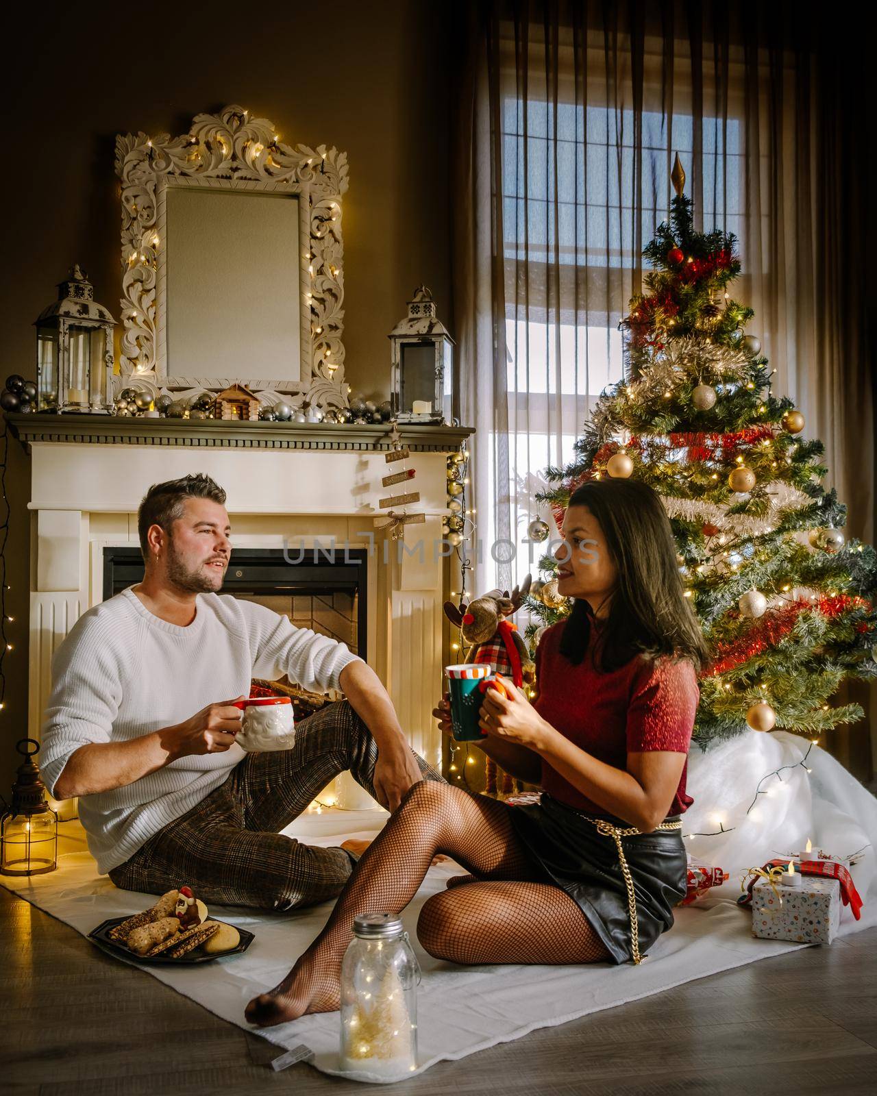 Family sitting on a floor. Couple near christmas tree, Christmas couple with present under christmas tree