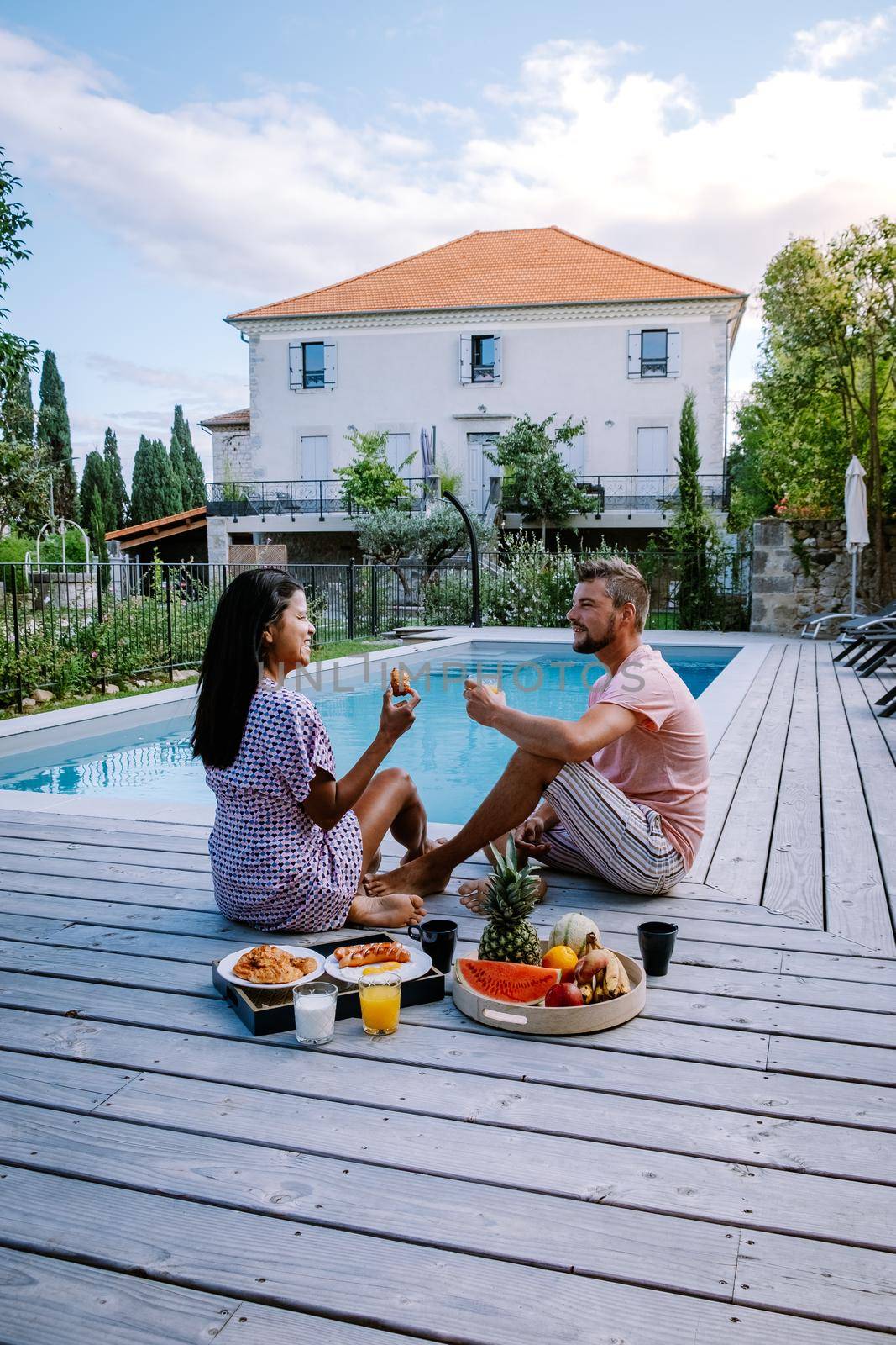 French vacation home with wooden deck and swimming pool in the Ardeche France. Couple relaxing by the pool with wooden deck during luxury vacation at an holiday home in South of France by fokkebok