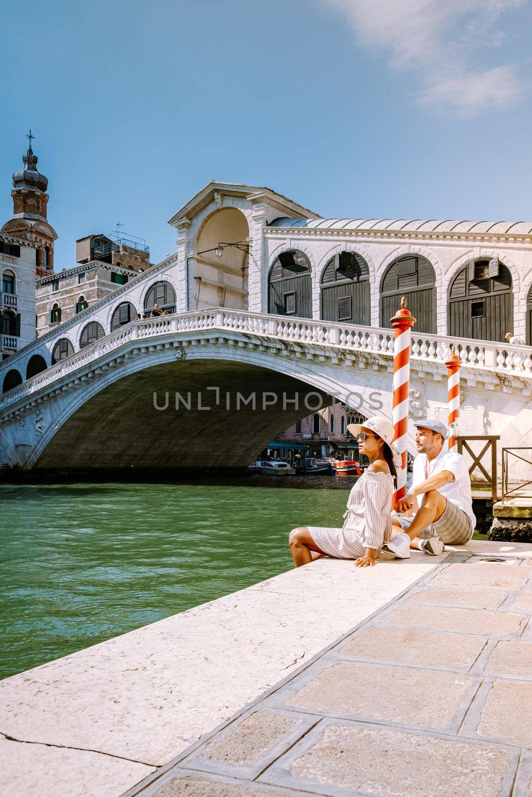 Venice Italy couple men and woman on a city trip at Venice, men and woman at waterfront looking at the famous Rialto bridge in Venice Italy by fokkebok