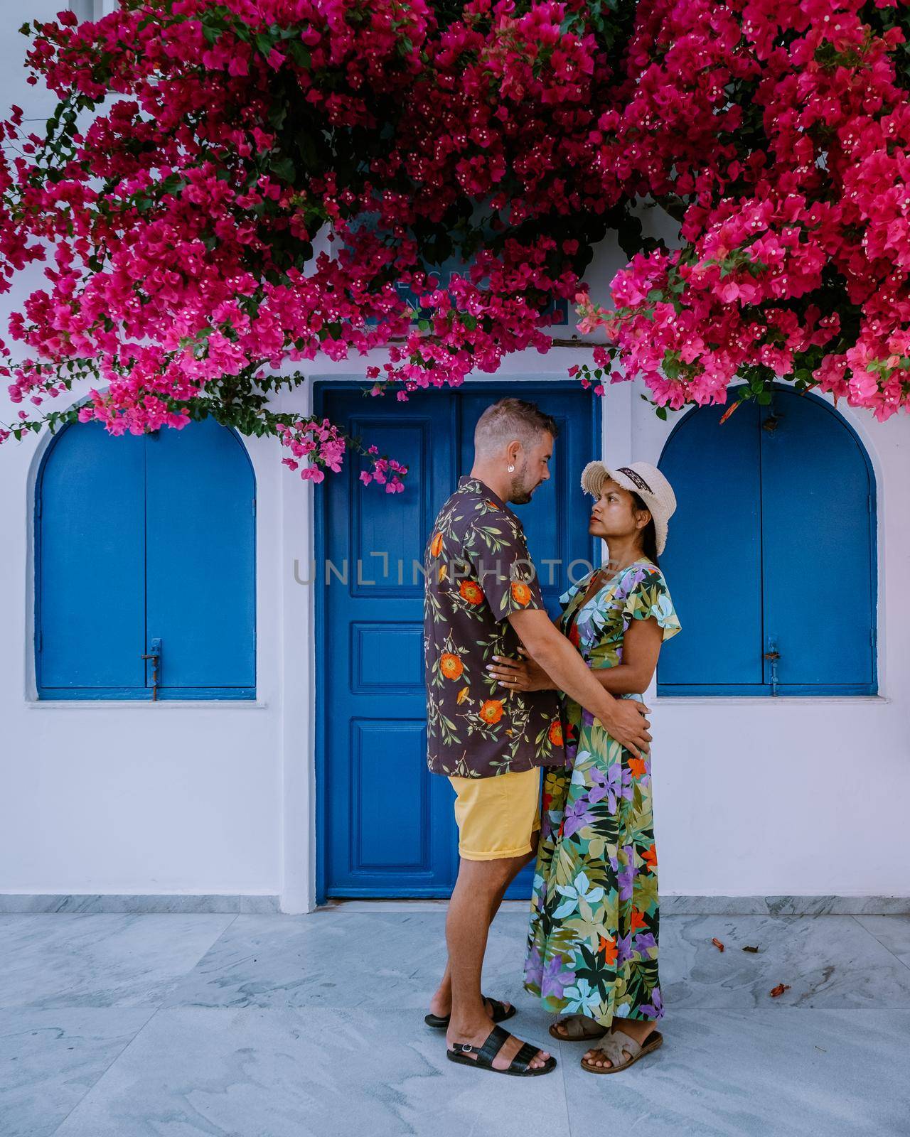 Santorini Greece, young couple on luxury vacation at the Island of Santorini watching sunrise by the blue dome church and whitewashed village of Oia Santorini Greece during sunrise during summer vacation, men and woman on holiday in Greece