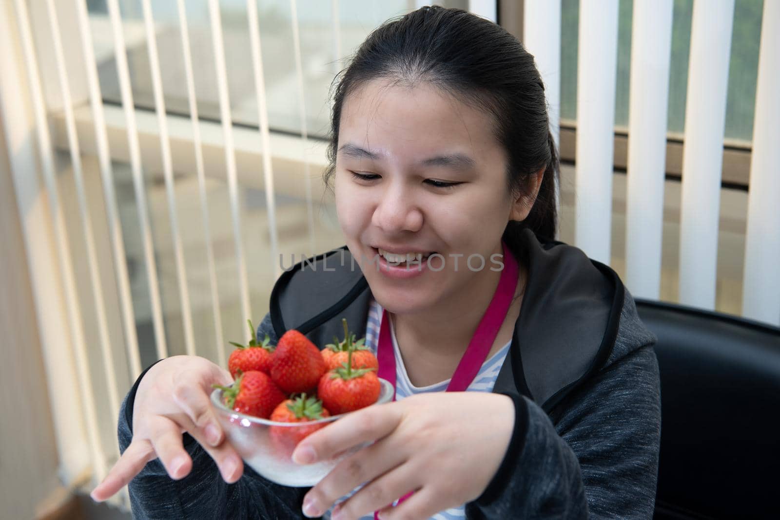 Asian pretty woman holding and eating fresh strawberry is red berry fruit color and sweet juicy with enjoy and happy emotion in concept food, healthy eating in life