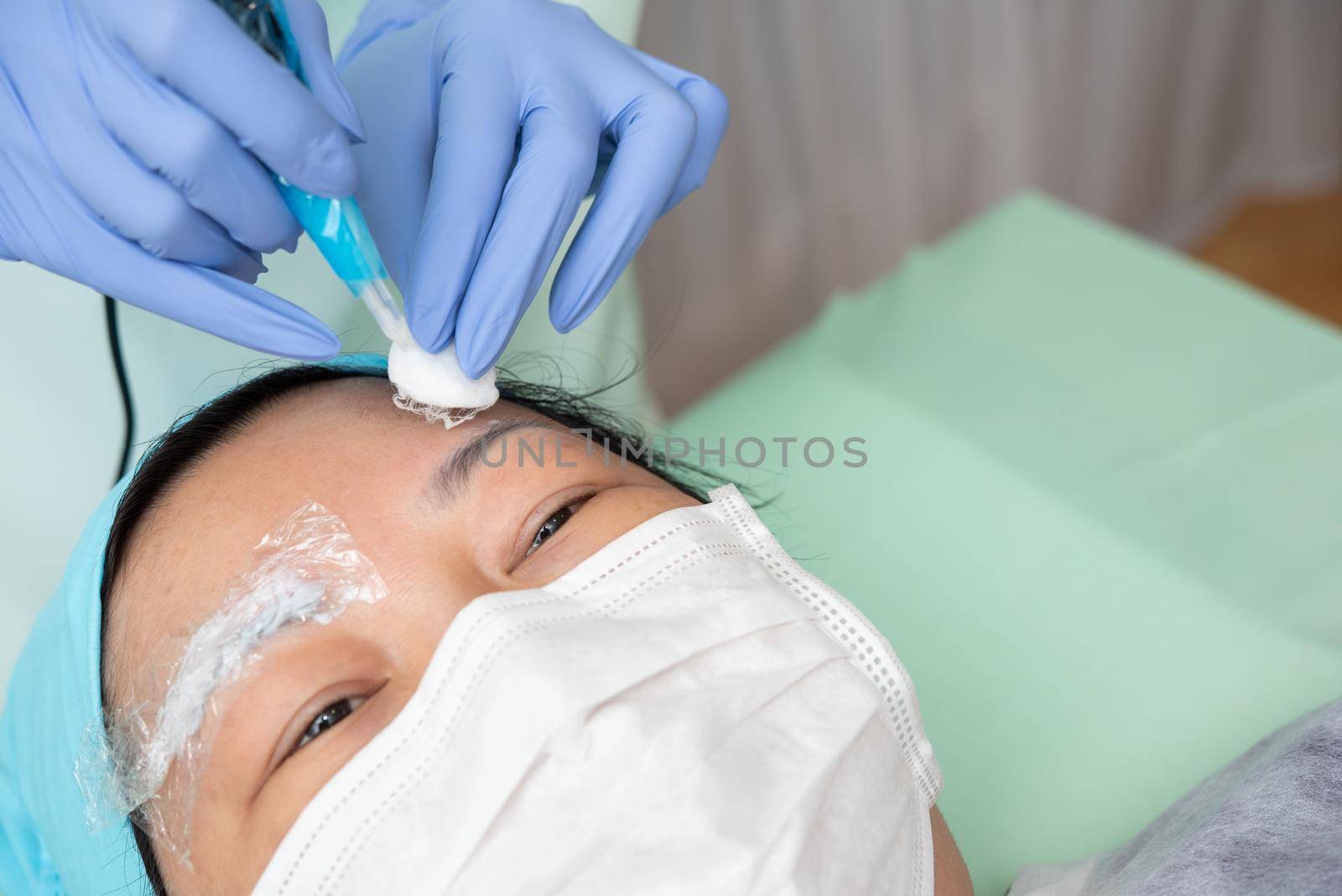 Asian woman eyebrow tattooing by doctor specialist in Eyebrow tattoo clinic or Eyebrow embroidery clinic for tattoo or correction use COVID-19 prevention policy protect by use mask and face shield
