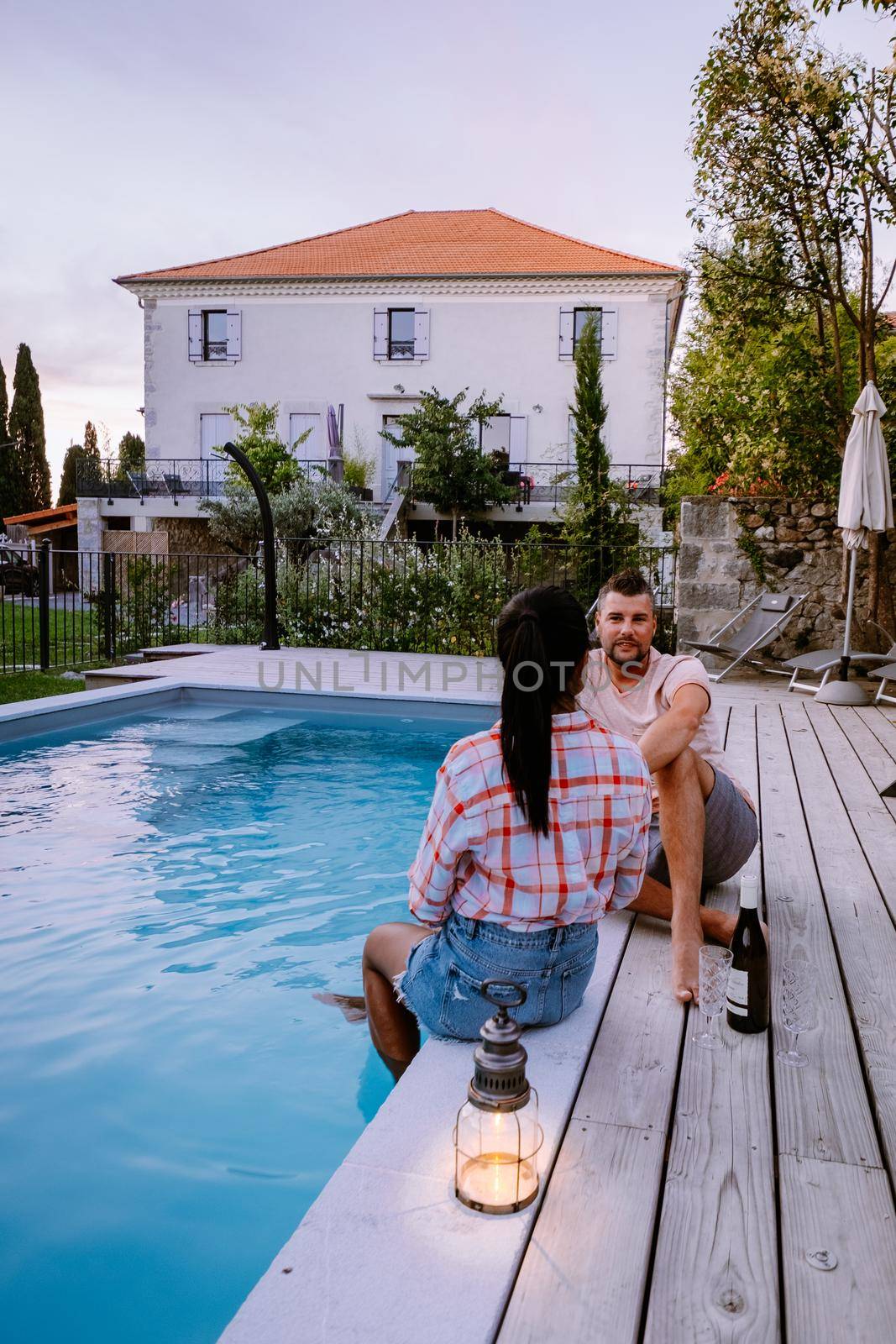 French vacation home with wooden deck and swimming pool in the Ardeche France Europe. Couple relaxing by the pool with wooden deck during luxury vacation at an holiday home in South of France