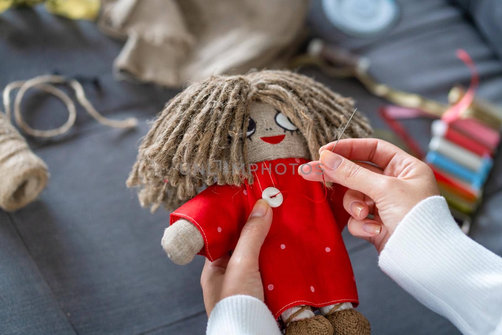 Handicraft is a fascinating hobby. The person sews dolls at their leisure.