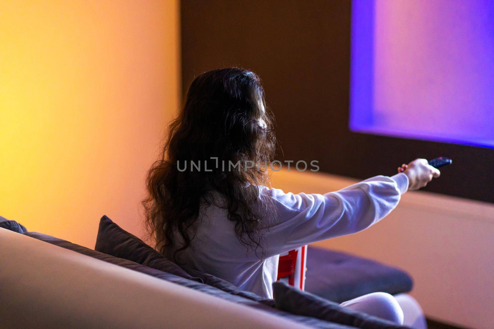 person watches a movie sitting on the couch with a bucket of popcorn.