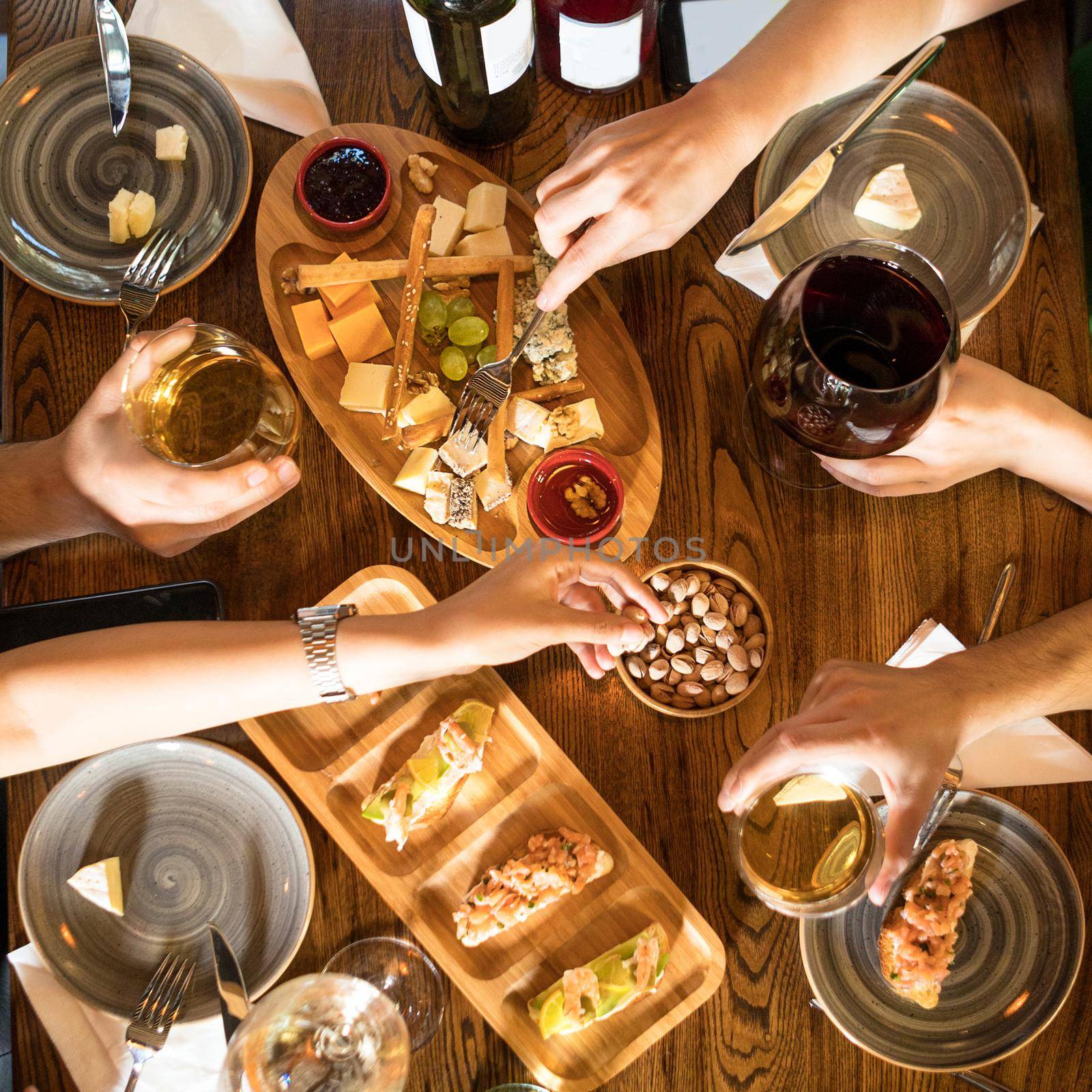 People drinking wine, eating snacks at the restaurant, top view
